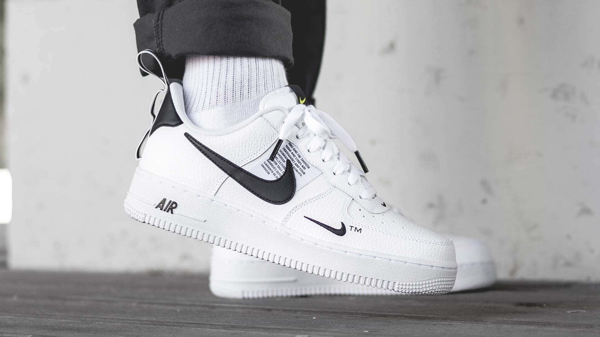 白色Nike Air Force 1波鞋配黑色剔標誌，同坑紋襪一齊放喺木地板上面。