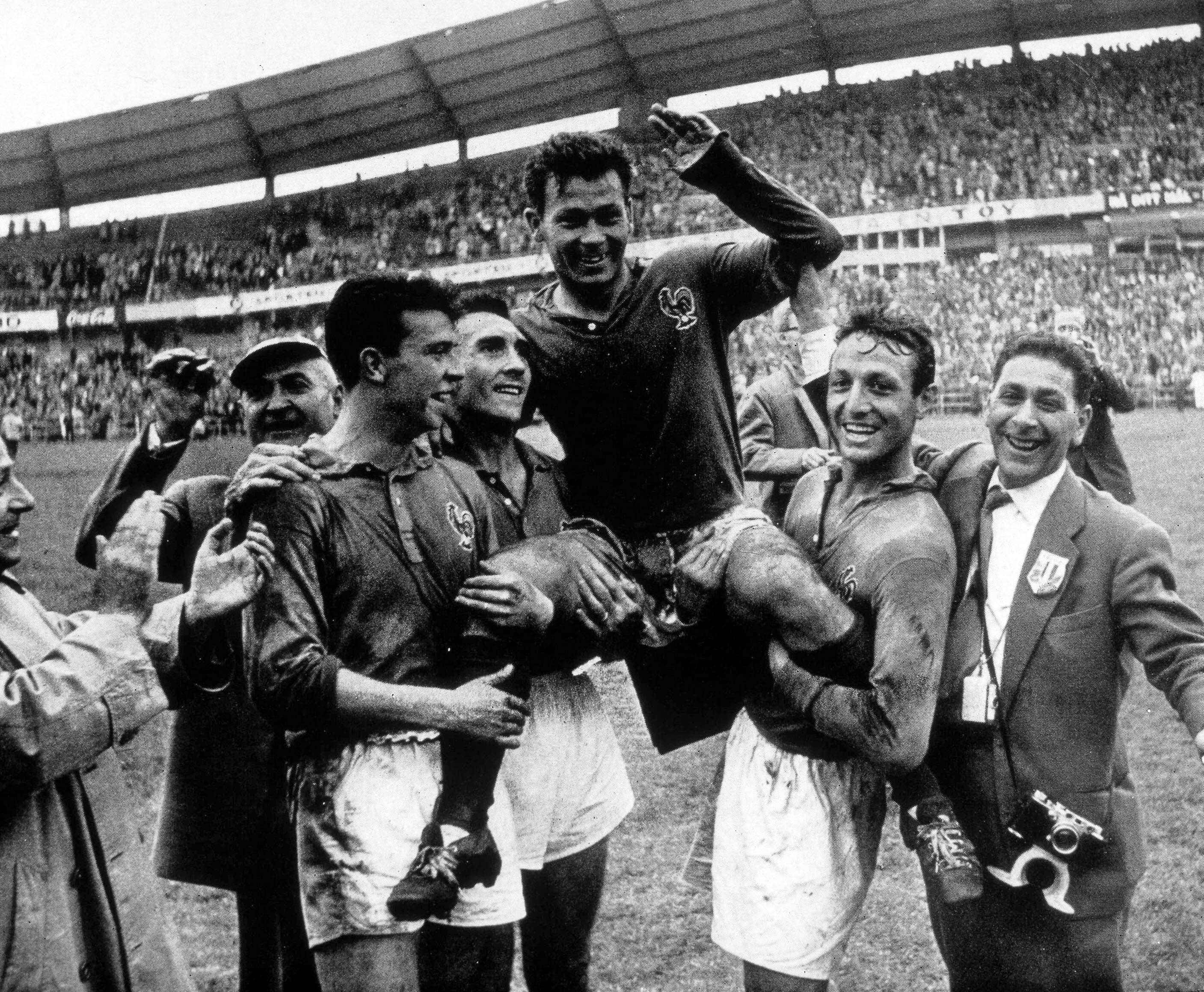 Just Fontaine 在 1958 年 FIFA 世界盃射門的經典瞬間 壁紙 — 黑白照片，法國足球運動員在擠滿觀眾的體育館中歡欣慶祝勝利。