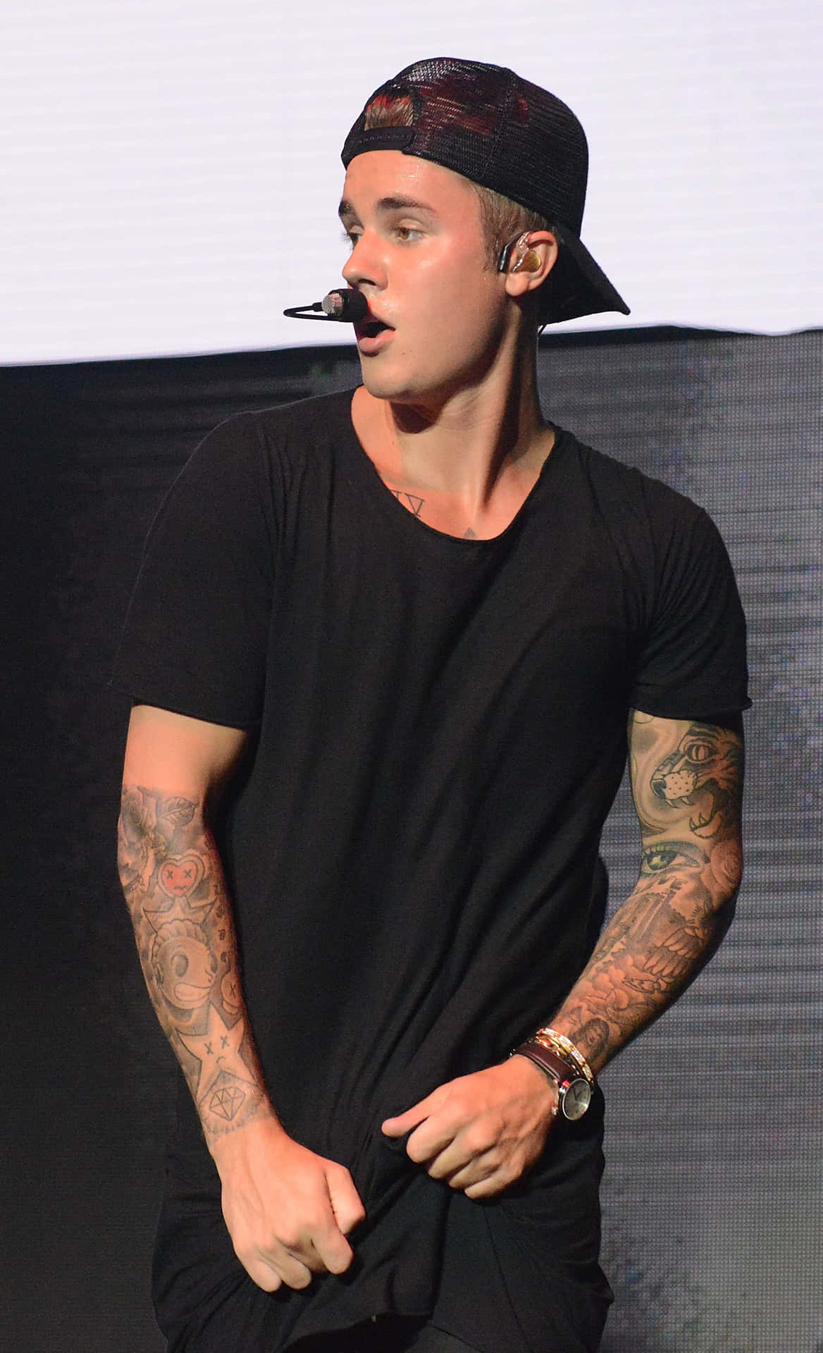 Justin Bieber 在舞台上唱歌，手臂上的紋身清晰可見。