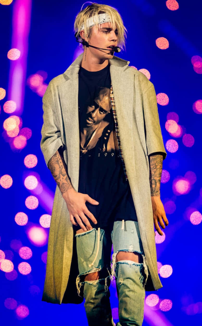 Justin Bieber 喺舞台上表演，背後有紫色同粉紅色燈光。