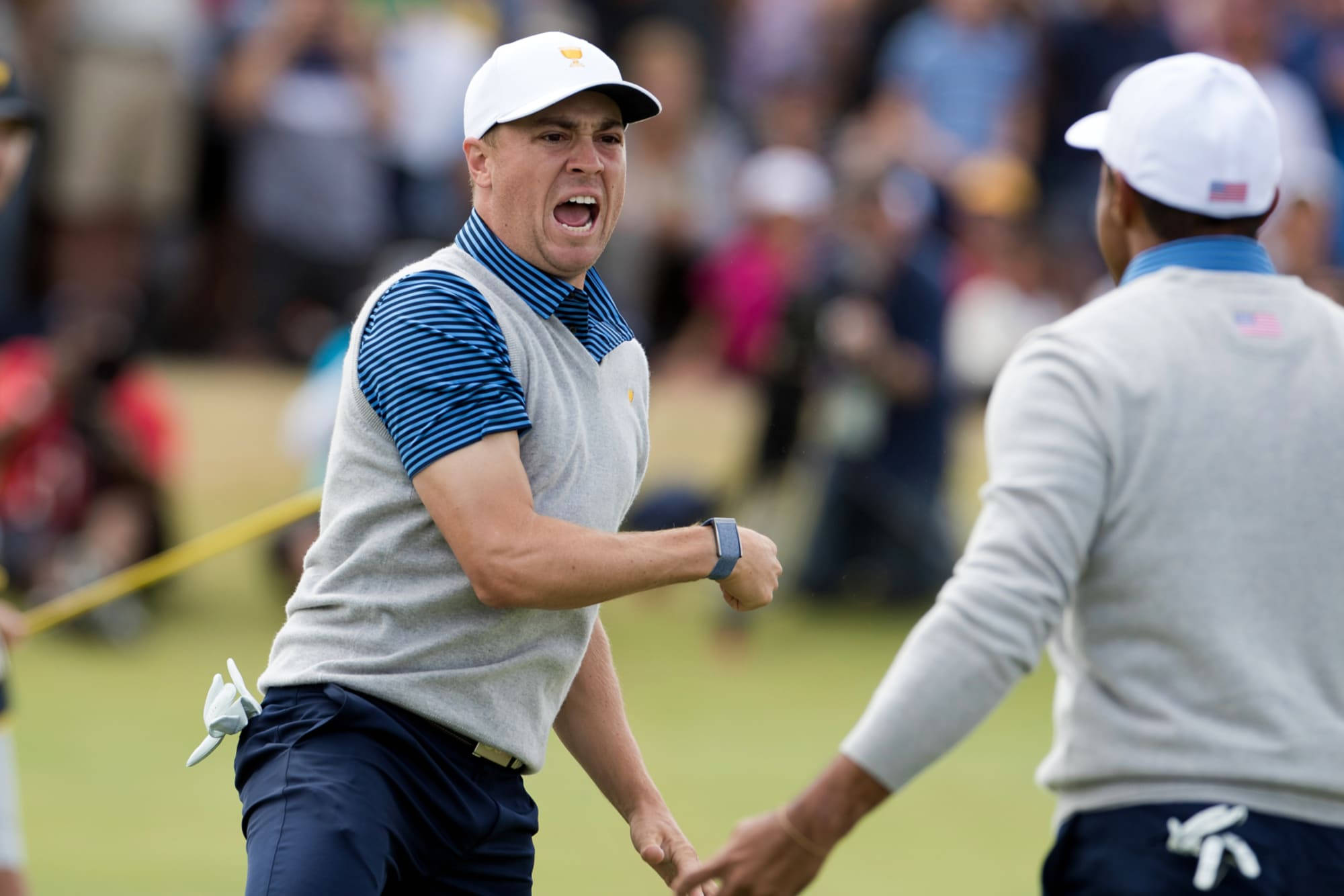 Justin Thomas 高聲吶喊 壁紙 — 一名高爾夫球手在陽光明媚的球場上與隊友握手時發出勝利的吶喊。