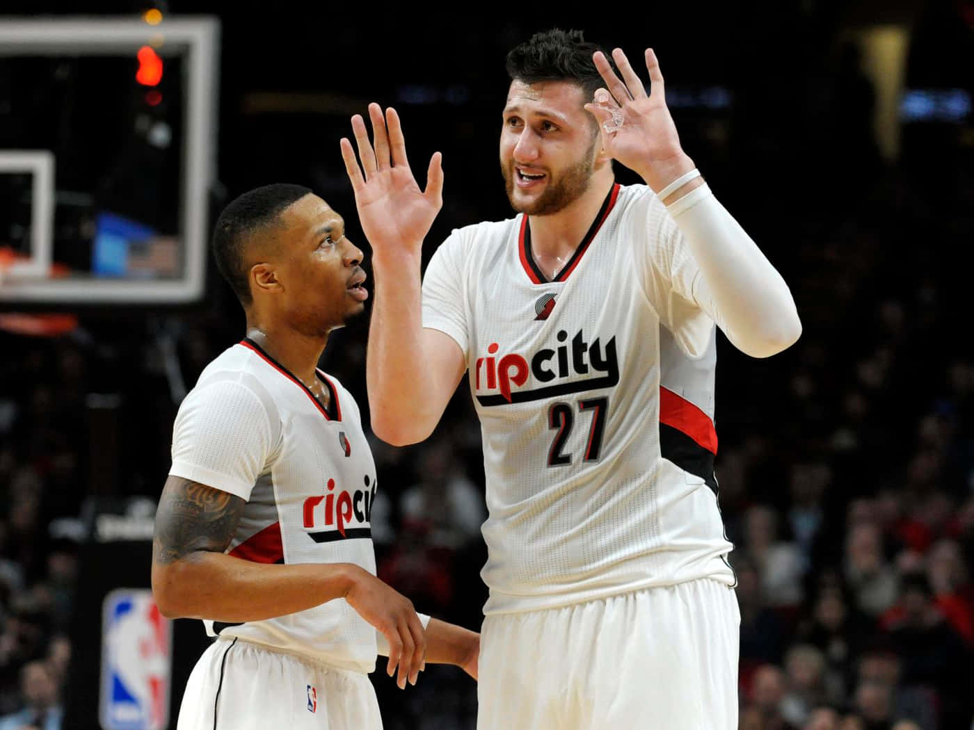Jusuf Nurkic 與 Damian Lillard 場上合照 壁紙 — 兩名身穿白色Rip City球衣的籃球運動員在比賽中於場館燈光下擊掌。