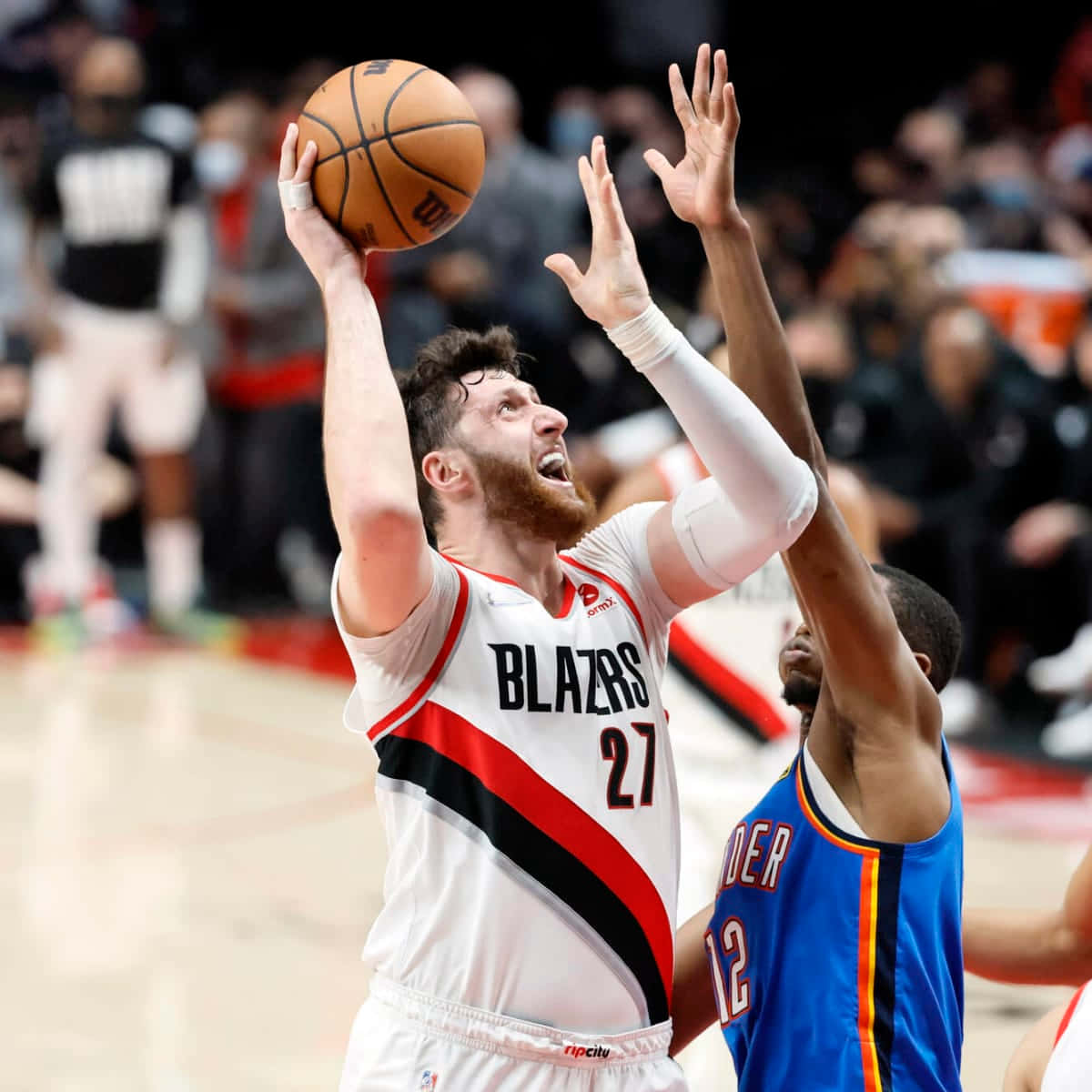 Jusuf Nurkic 與 Lindy Waters III 壁紙 — 一位身穿白色Blazers球衣的籃球運動員跳投，而一位身穿藍色球衣的防守球員伸手阻擋。