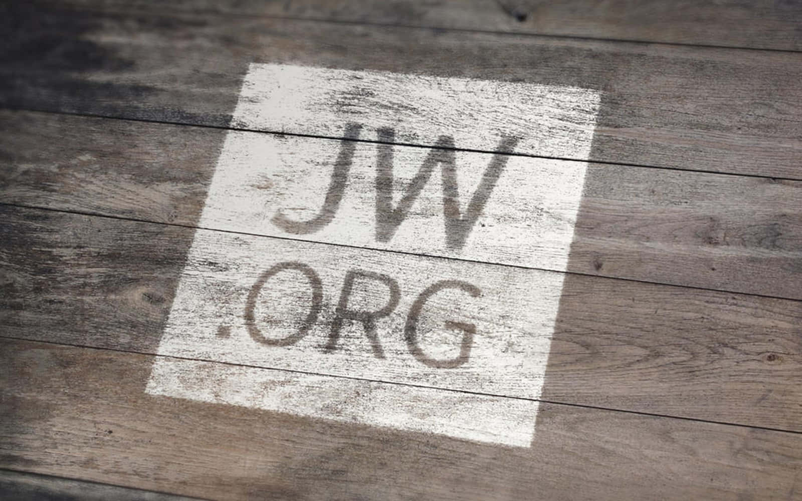 JWorg於木板表面 壁紙 — 一個風化的木地板，上面有褪色的白色方形投影，顯示文字 JW.ORG。