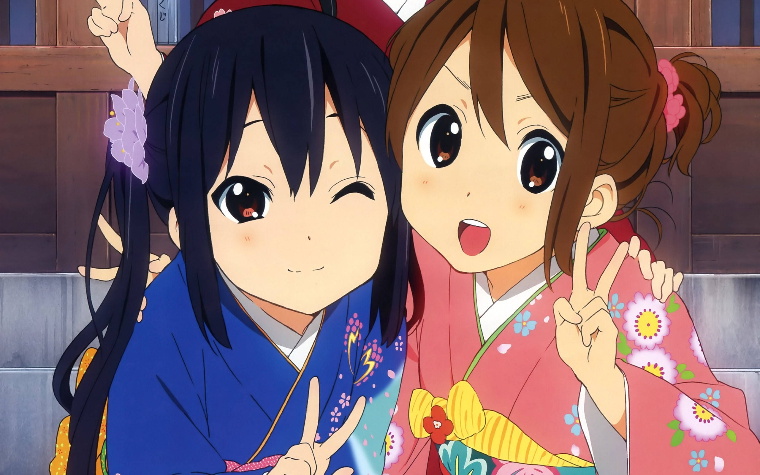 K-on 唯與律穿和服 壁紙 — 兩個穿著色彩繽紛和服的開朗動漫女孩在木質背景前擺出和平手勢。