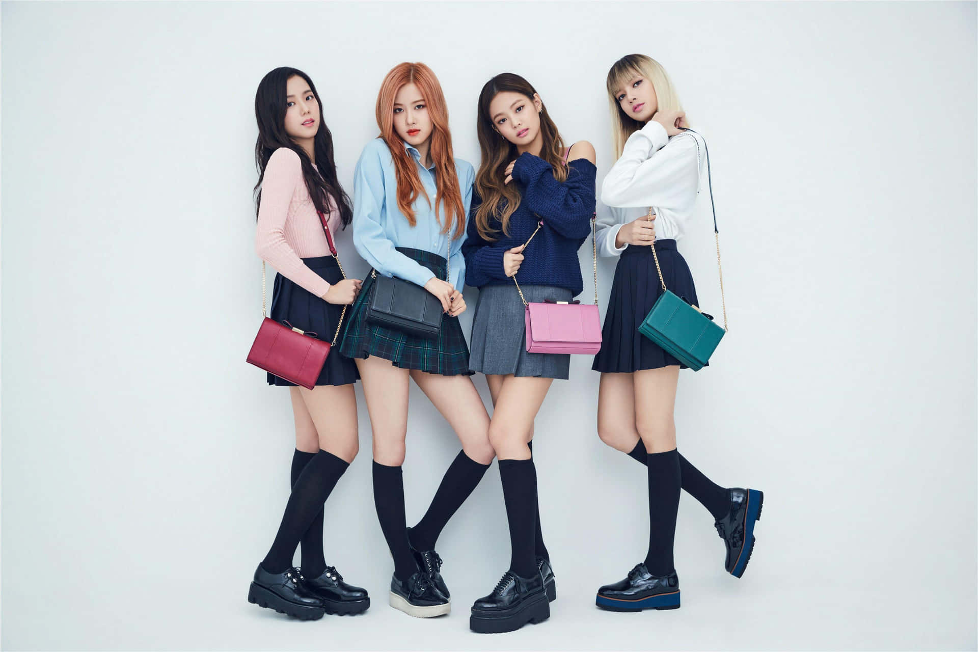 K-POP 熱潮 BLACKPINK 女孩，全球女性粉絲的靈感與力量來源 壁紙 — 四位時尚年輕女性穿著協調的校服，在純白背景前自信地擺姿勢。