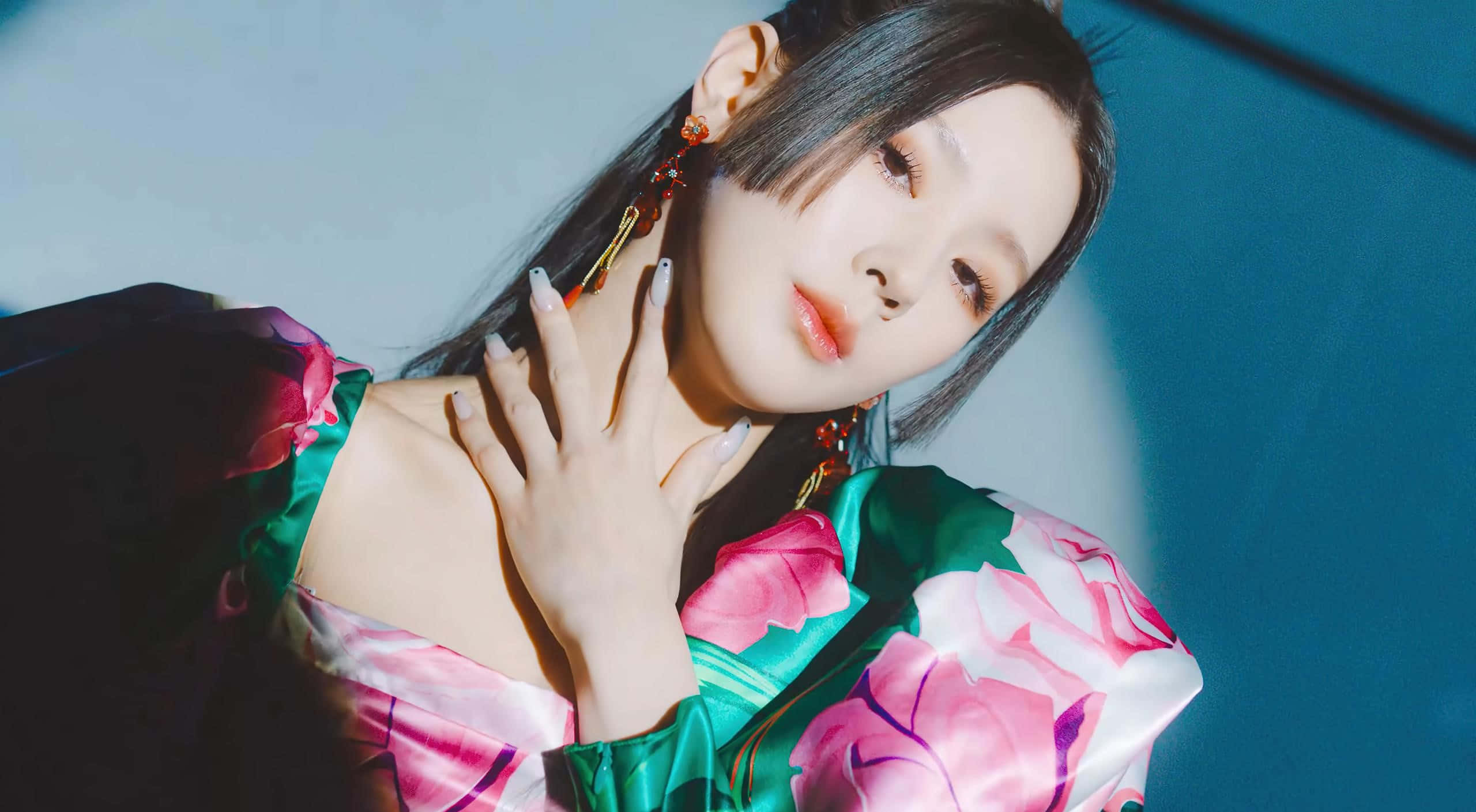 K-pop 組合搭配戲劇性背景 壁紙 — 一位身穿花卉緞面睡袍的女性在戲劇性的藍色燈光下，將手放在脖子上擺姿勢。