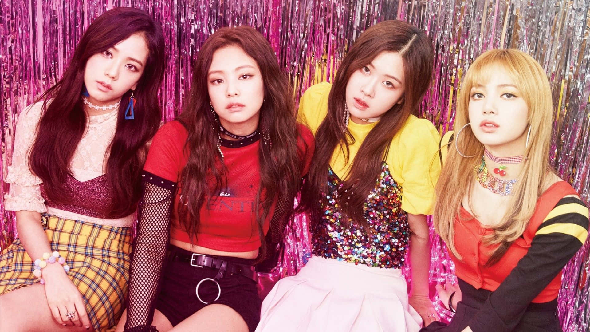 K-pop組合穿時尚街頭服裝拍攝 壁紙 — 四位時尚女性在閃爍的粉紅色金屬箔背景前，穿著大膽多彩的服裝自信地擺姿勢。