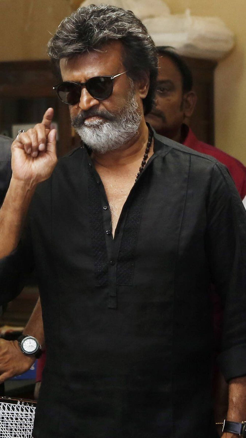 拉吉尼坎塔在《Kaala》中飾演卡里卡蘭 壁紙 — 一位留著灰色鬍鬚、戴著太陽眼鏡的男子，在室內穿著黑色襯衫，用手指做手勢。