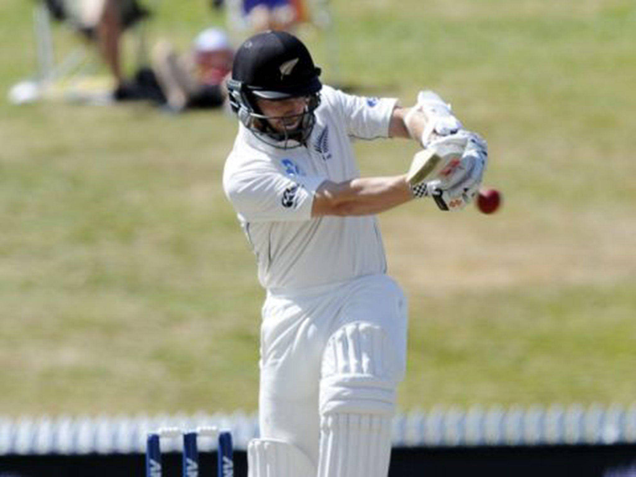 Kane Williamson 板球場 壁紙 — 一名穿著白色球衣的板球擊球手在陽光明媚的日間比賽中，在草地上揮動球棒擊打紅色球。