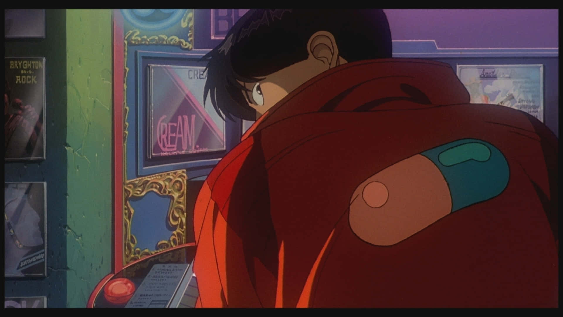 Kaneda 後視圖 壁紙 — 一個穿著紅色外套的年輕動漫男孩在霓虹燈閃爍的遊戲機中心，越過肩膀回頭看，周圍有裱框海報。