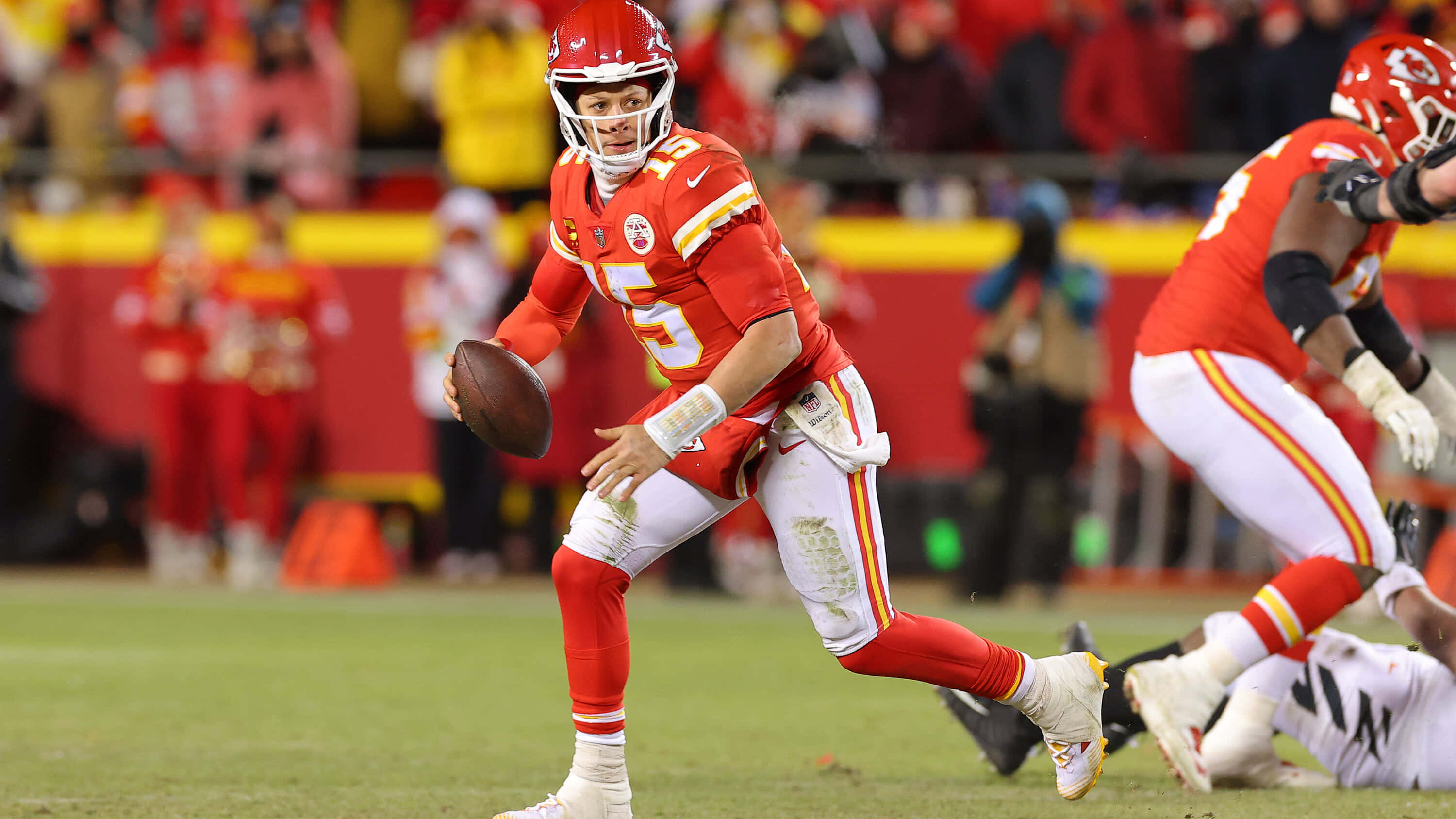 NFL Quarterbacks 桌布 壁紙 — 堪薩斯城酋長隊的四分衛身穿紅色球衣，在體育館燈光下的夜間比賽中準備投擲橄欖球。