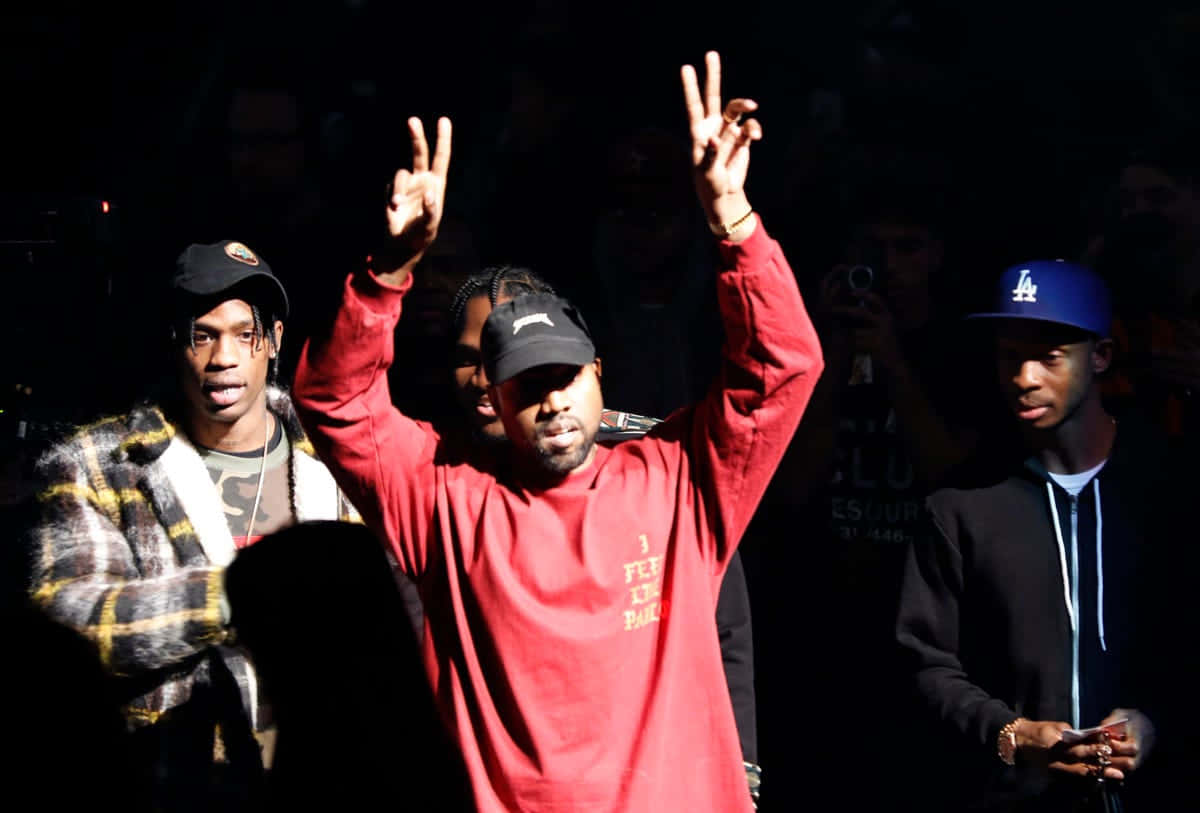 Kanye West《The Life of Pablo》專輯封面藝術 壁紙 — 三名男子在昏暗的演唱會燈光下舉起和平手勢，中間一人身穿紅衫黑帽。