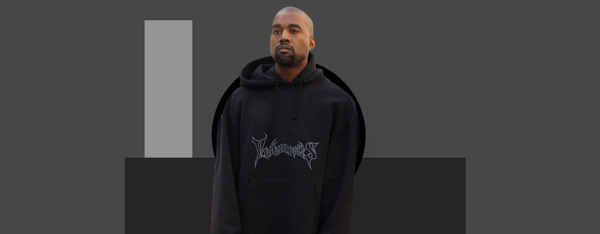 Kanye West Vetements 拍攝 壁紙 — Kanye West 身處簡約風格的工作室，身穿帶有銀色圖案的黑色連帽衫，背景為單色幾何圖案。