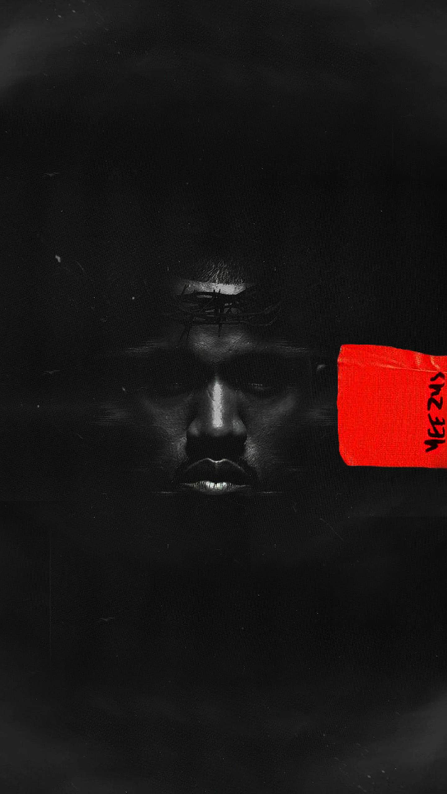 Kanye West黑白肖像 壁紙 — 一張強烈的黑白肖像，男人的臉部分被陰影遮擋，一隻眼睛上貼著一張大膽的紅色貼紙。