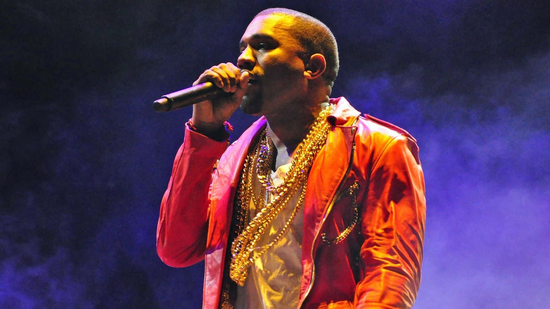 Kanye 桌布 壁紙 — Kanye West 在舞台上穿著紅色外套和金色鏈條，在戲劇性的藍色燈光下表演。