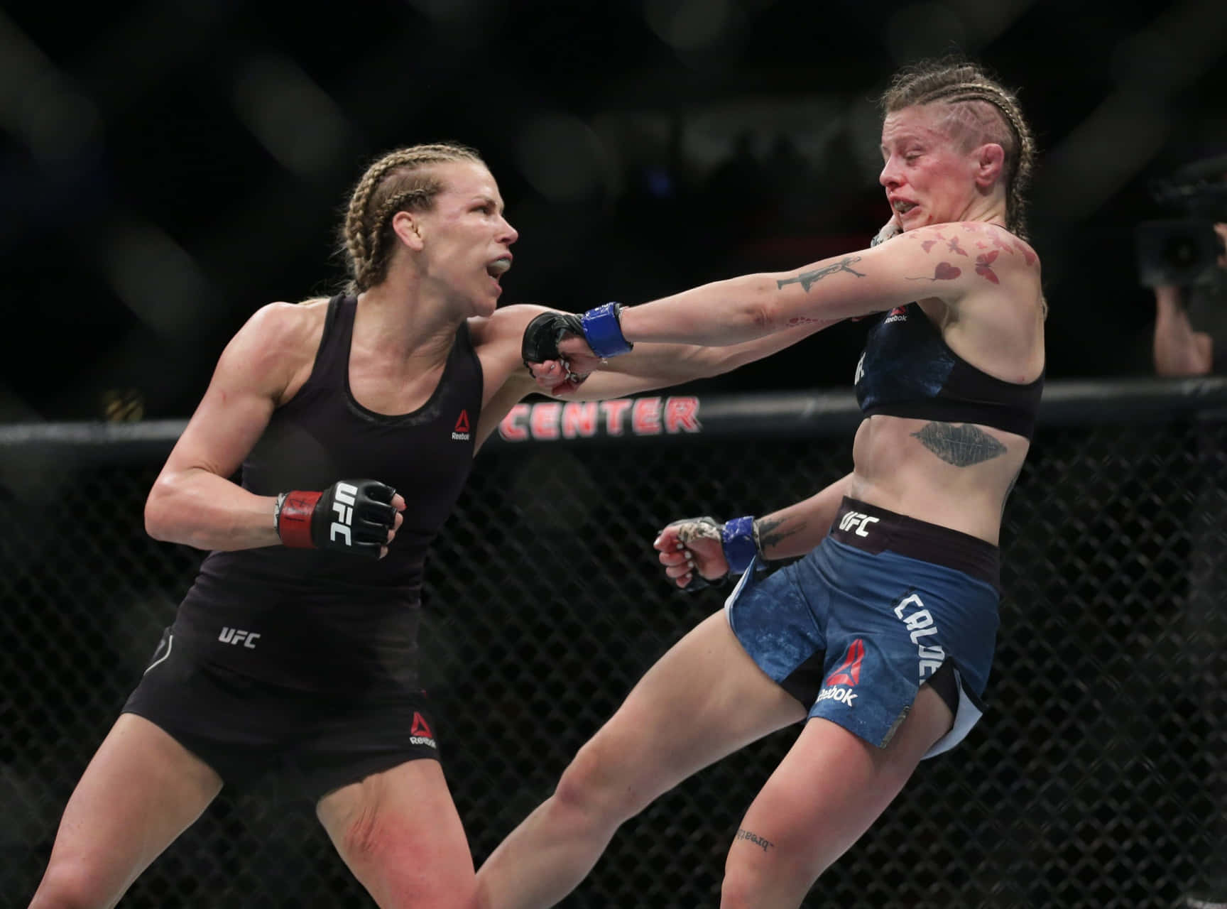 Katlyn Chookagian 激烈搏鬥 壁紙 — 兩名女性MMA拳手在明亮的場館燈光下進行激烈的籠鬥，汗水和紋身清晰可見。