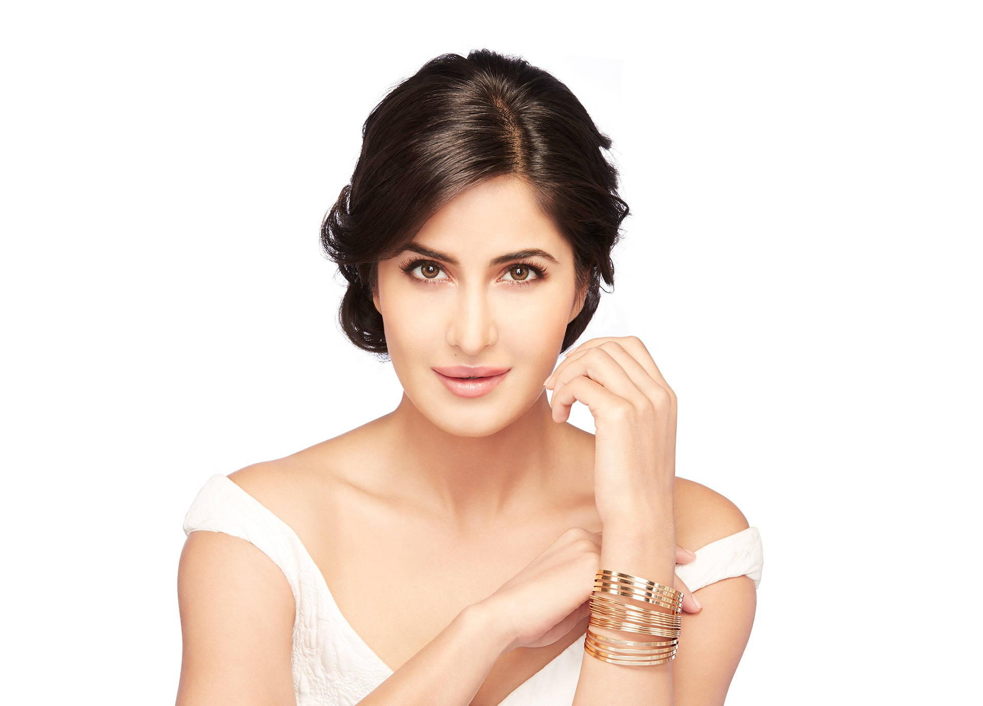 Katrina Kaif L'Oreal Paris護膚廣告照 壁紙 — 一位深色頭髮、戴著金手鐲的女性，穿著白色露肩上衣，在純白背景前優雅地擺姿勢。