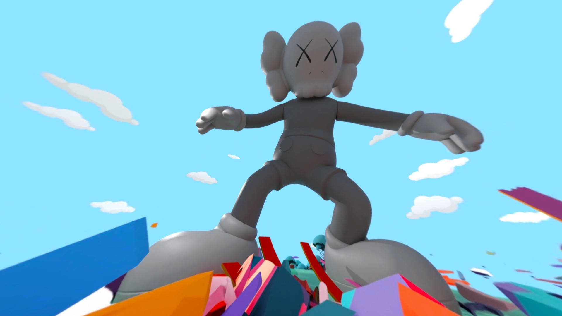 KAWS Companion從下方視角 壁紙 — 一個灰色的KAWS人偶勝利地站在一堆色彩繽紛的幾何碎片上，背景是晴朗的藍天和蓬鬆的白雲。