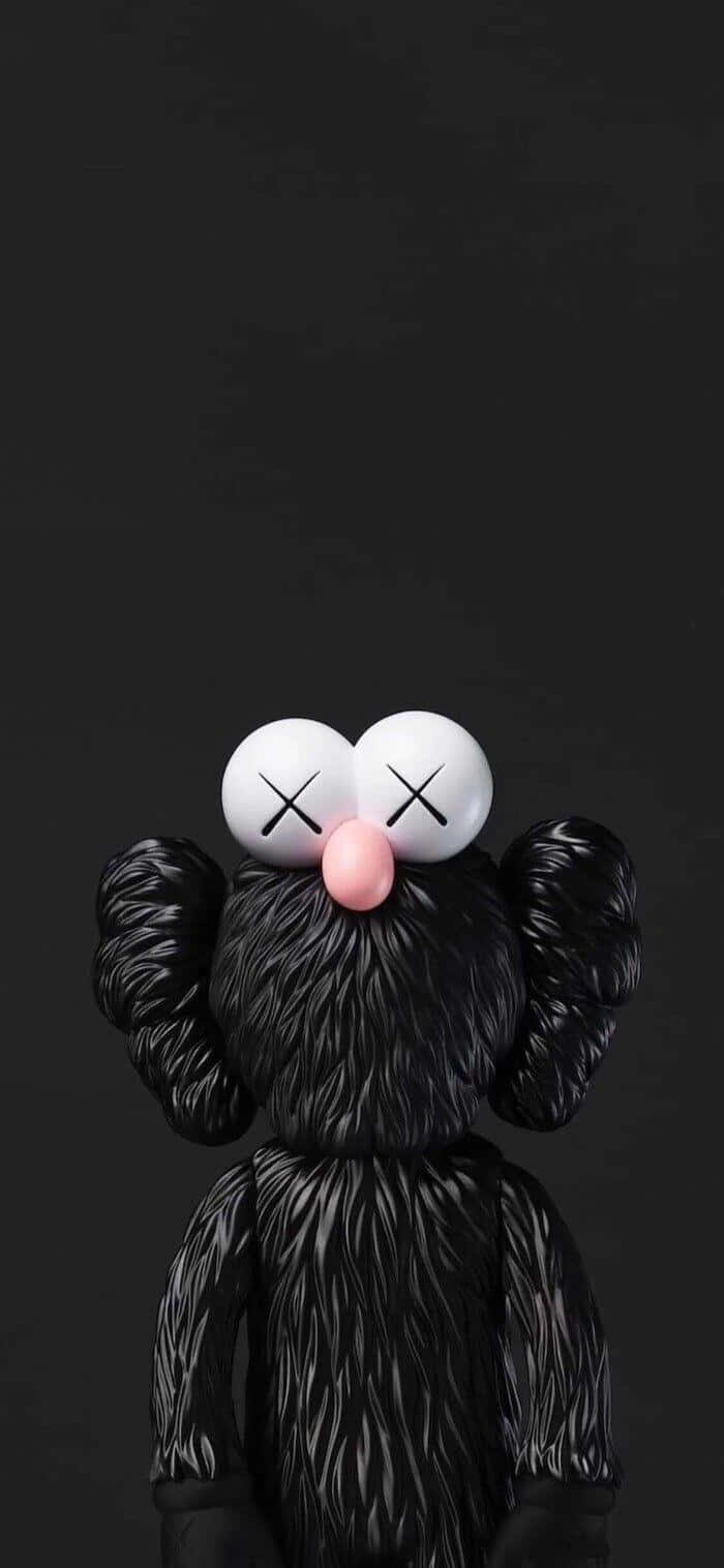 「讓藝術活現：KAWS X UNIQLO聯名系列」 壁紙 — 一個黑色毛茸茸的KAWS角色，交叉的眼球和粉紅色的鼻子，在純黑色背景上向上凝視。