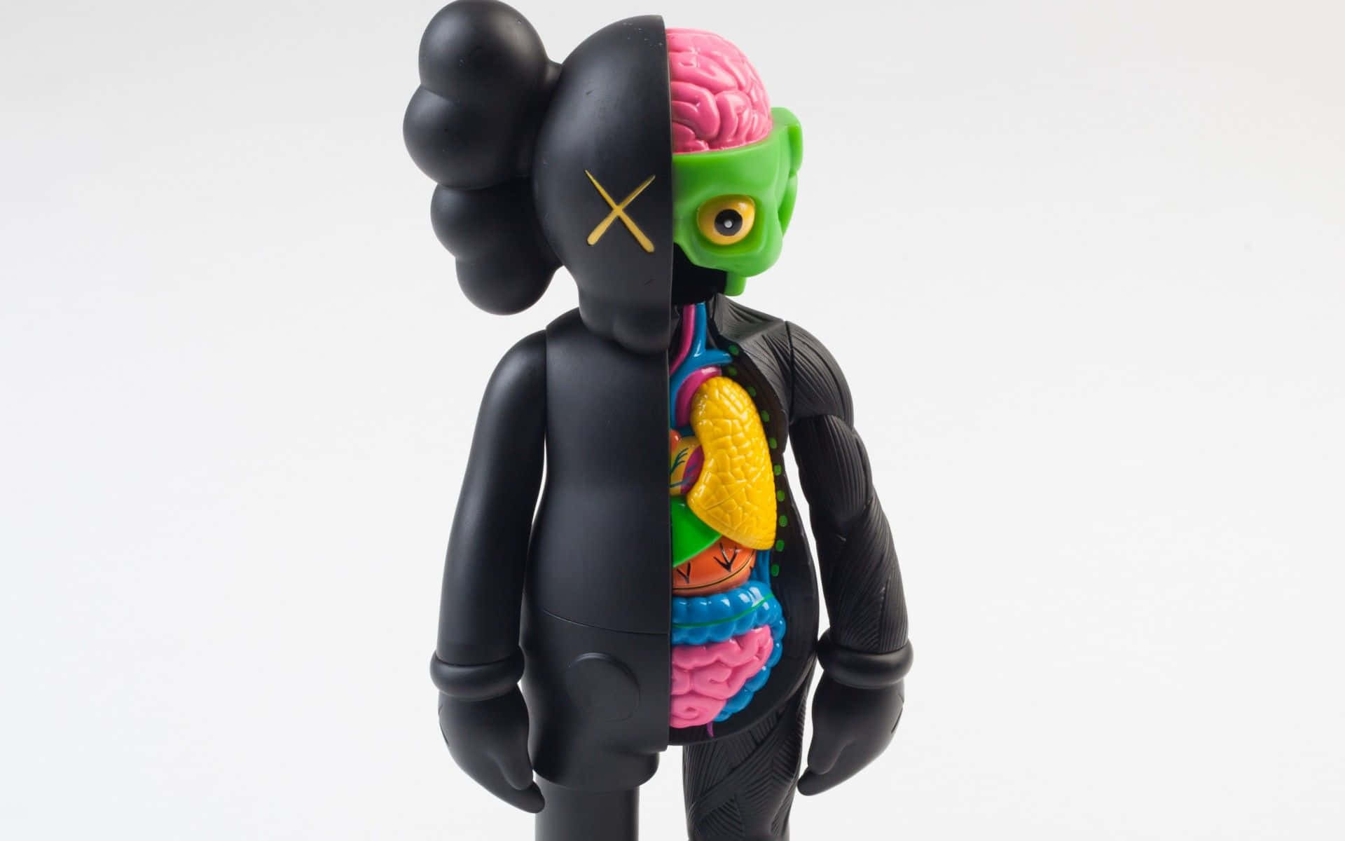 Kaws 的藝術風格 壁紙 — 一個黑色KAWS公仔被剖開，露出色彩繽紛的內臟和粉紅色大腦，背景為白色。