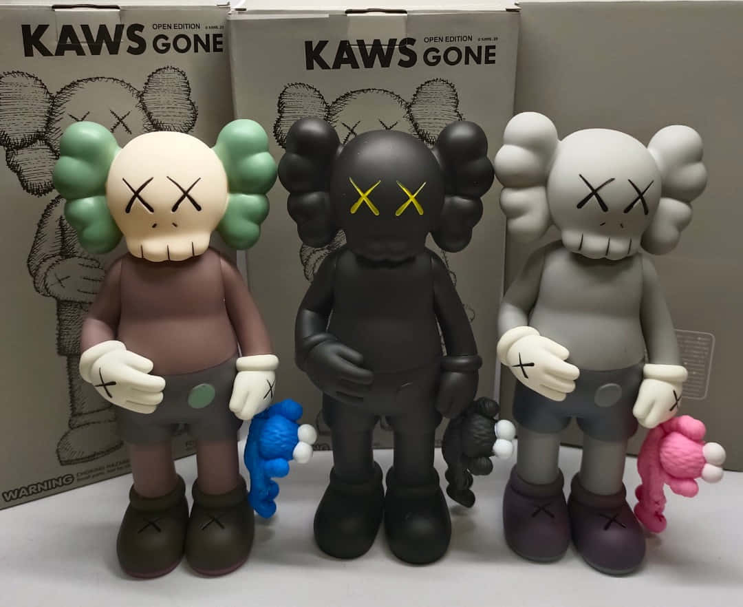 KAWS：融合歡樂與現代藝術的當代藝術家 壁紙 — 三隻米色、黑色和灰色的KAWS「Gone」搪膠公仔並排站立，手持毛絨玩具靠著其品牌盒子。