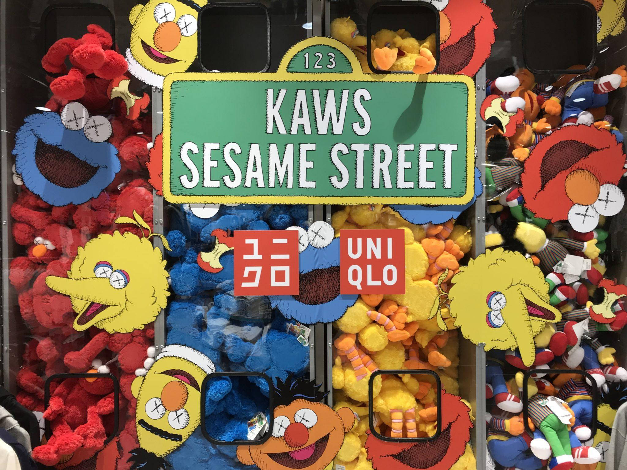 KAWS芝麻街聯名 壁紙 — 充滿 KAWS x 芝麻街毛絨玩具的活力夾公仔機，角色眼睛帶有 X 標記。
