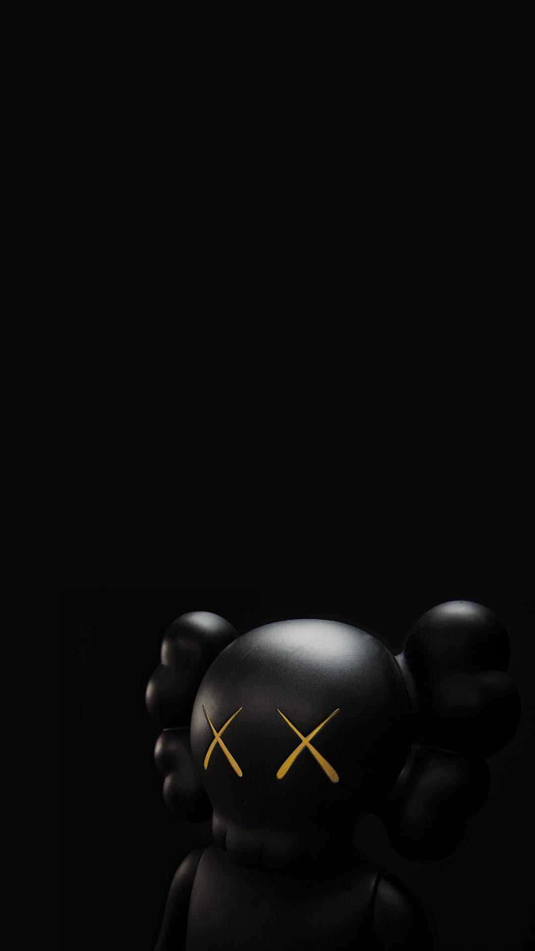 黑色KAWS人偶帶金色X眼睛，背景為黑色。