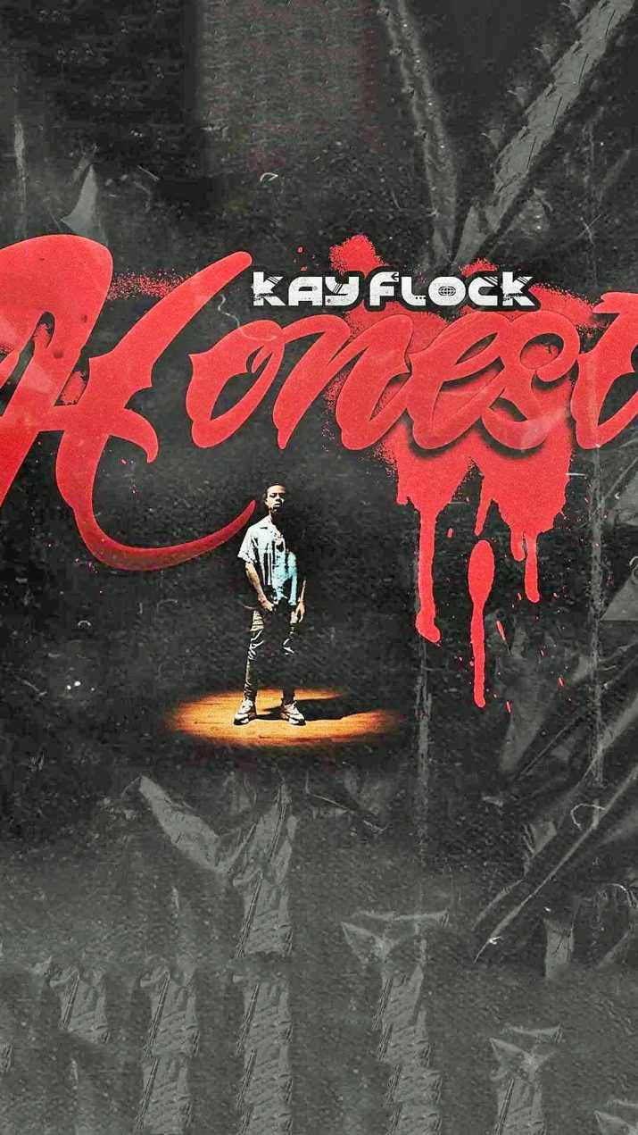 藝術家 Kay Flock 站在聚光燈下，深色牆壁上有紅色滴落的「Honest」文字。