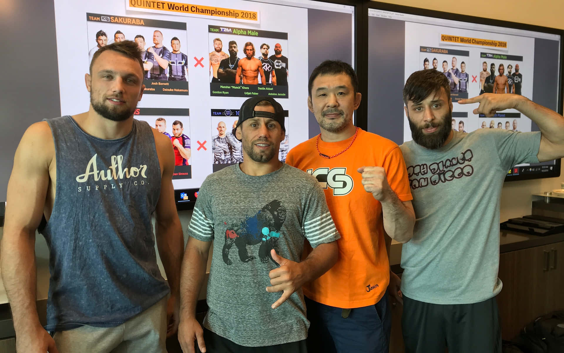 Kazushi Sakuraba 與 Quintet 團隊領袖合照 壁紙 — 四名男子自信地站在大型屏幕前，屏幕上顯示著Quintet World Championship 2018的選手對戰組合。