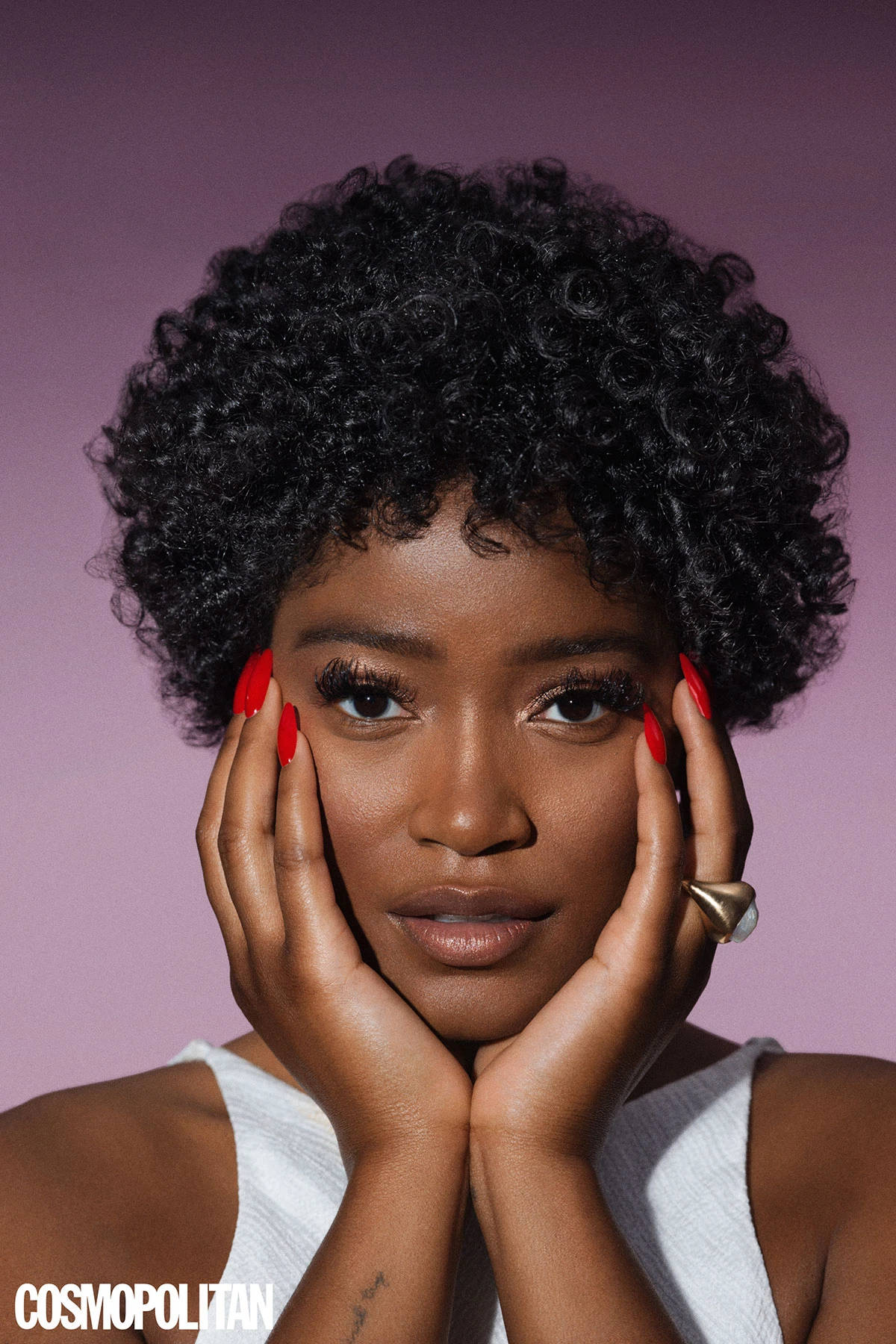 Keke Palmer 哥倫比亞時尚雜誌 壁紙 — 一位自信的女性，擁有豐盈的捲髮和紅色指甲，在柔和的紫色背景下用手框住臉龐。