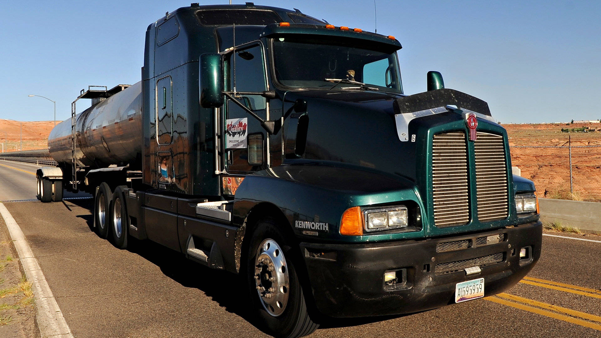 日落時分沙漠公路上的深綠色Kenworth油罐車。