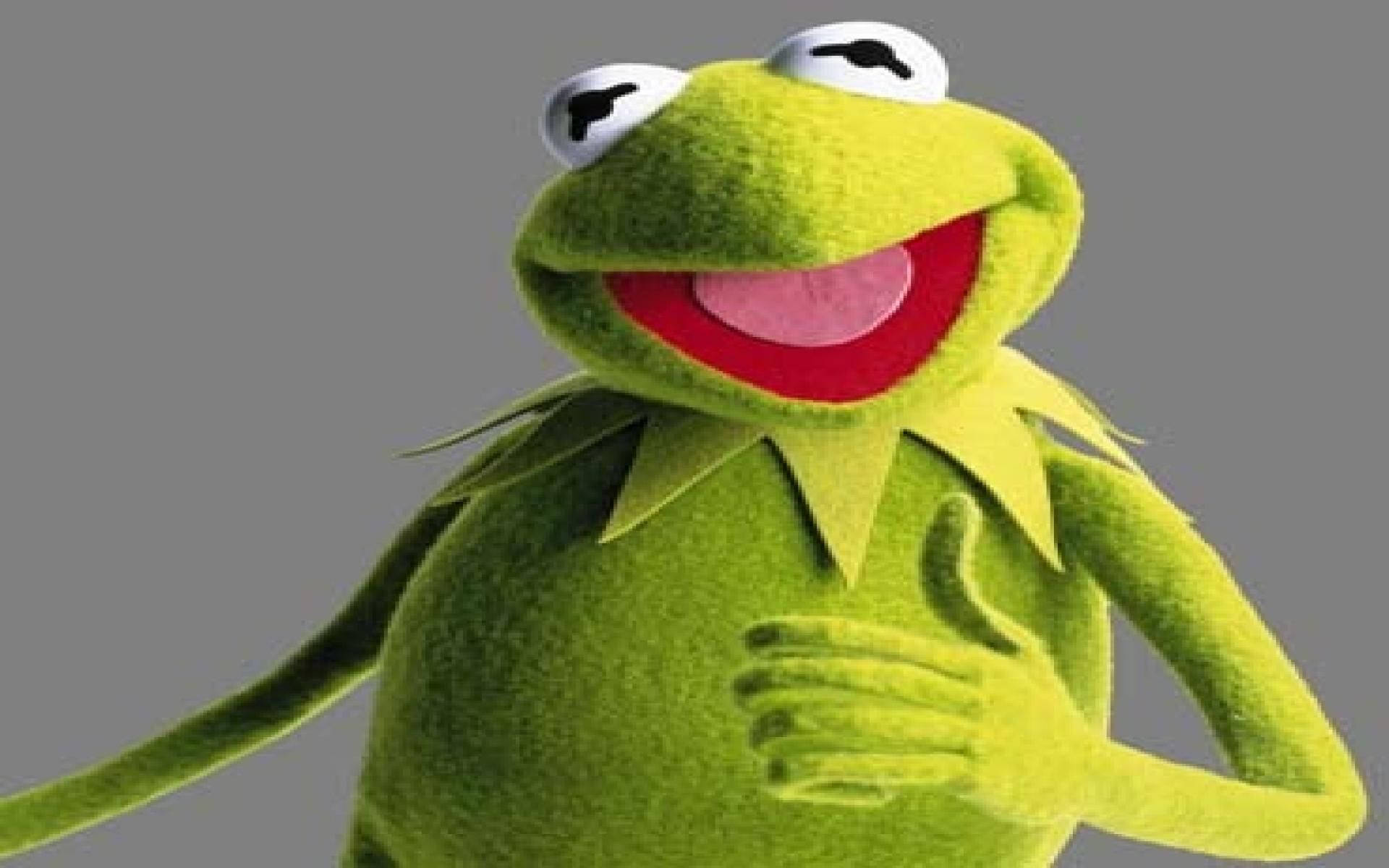 Kermit 領獎讚賞 壁紙 — 一隻快樂的綠色青蛙木偶，有著寬闊的紅嘴巴和白色的眼睛，在純灰色背景上豎起大拇指。