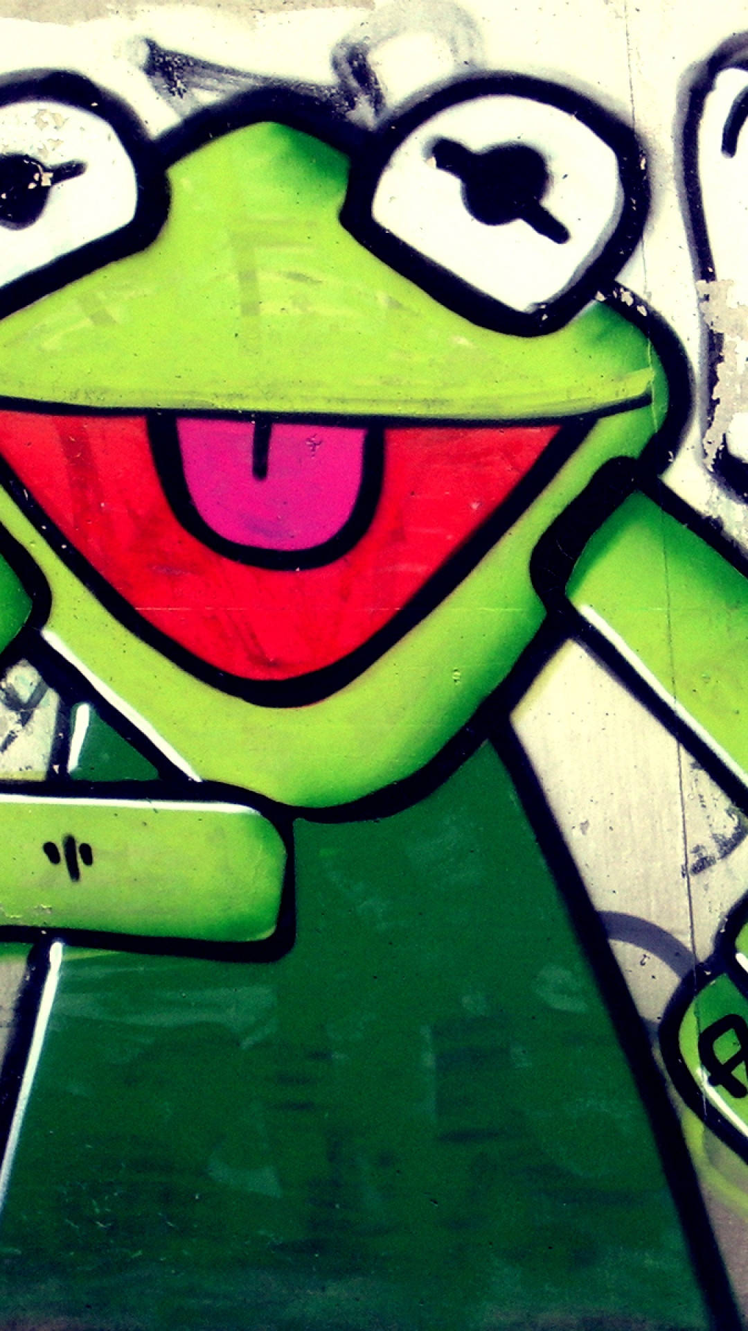 搞笑Keroppi藝術iPhone壁紙 壁紙 — 一幅充滿活力的塗鴉壁畫，描繪了青蛙柯密特，以粗線條和鮮豔色彩繪於風化的城市牆上。
