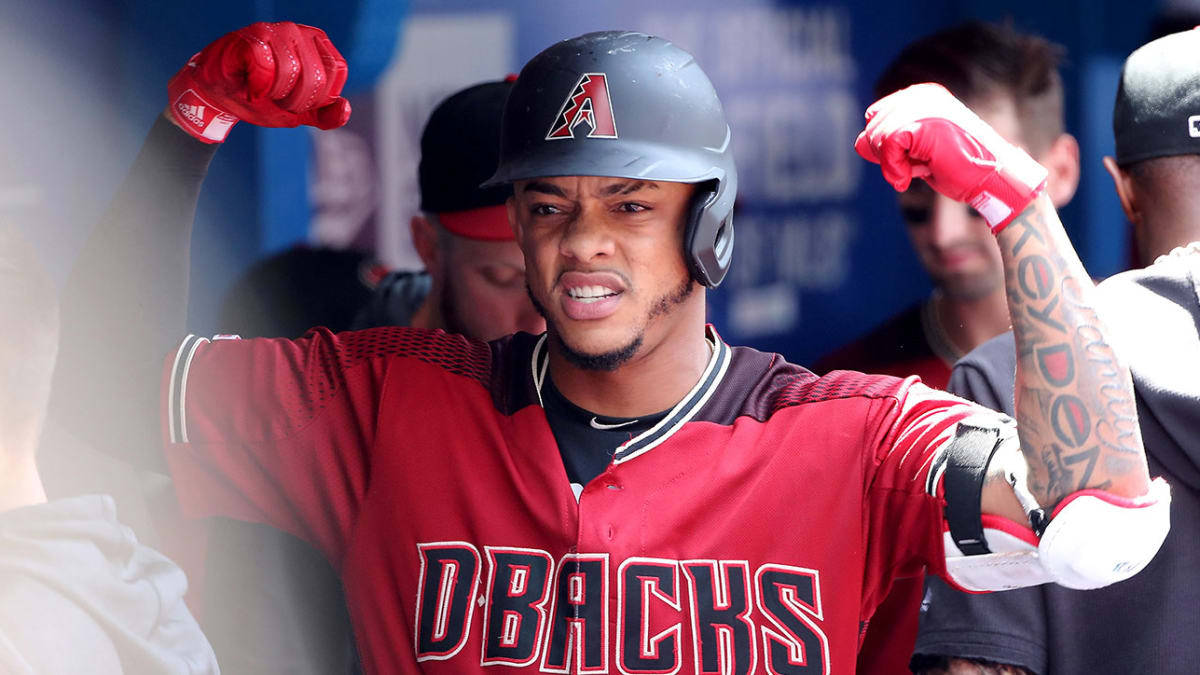 Ketel Marte 展示臂力 壁紙 — 身穿紅色DBacks球衣的棒球運動員在球員休息區彎曲手臂，表情強烈。