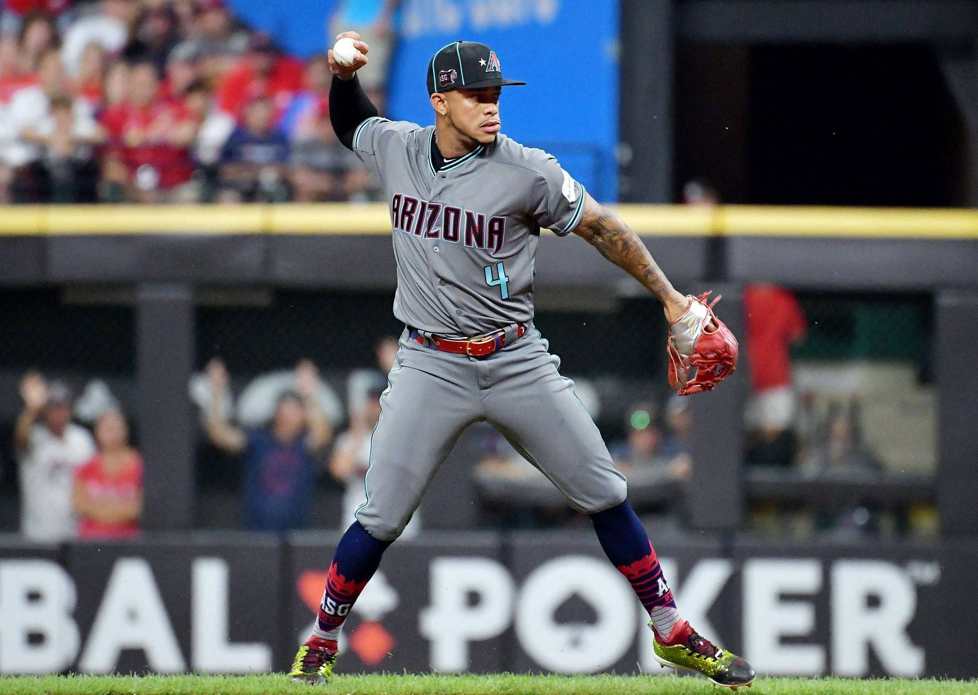 Ketel Marte 投球 壁紙 — 一名身穿亞利桑那隊服的棒球選手在燈光球場上投球，背景有球迷。
