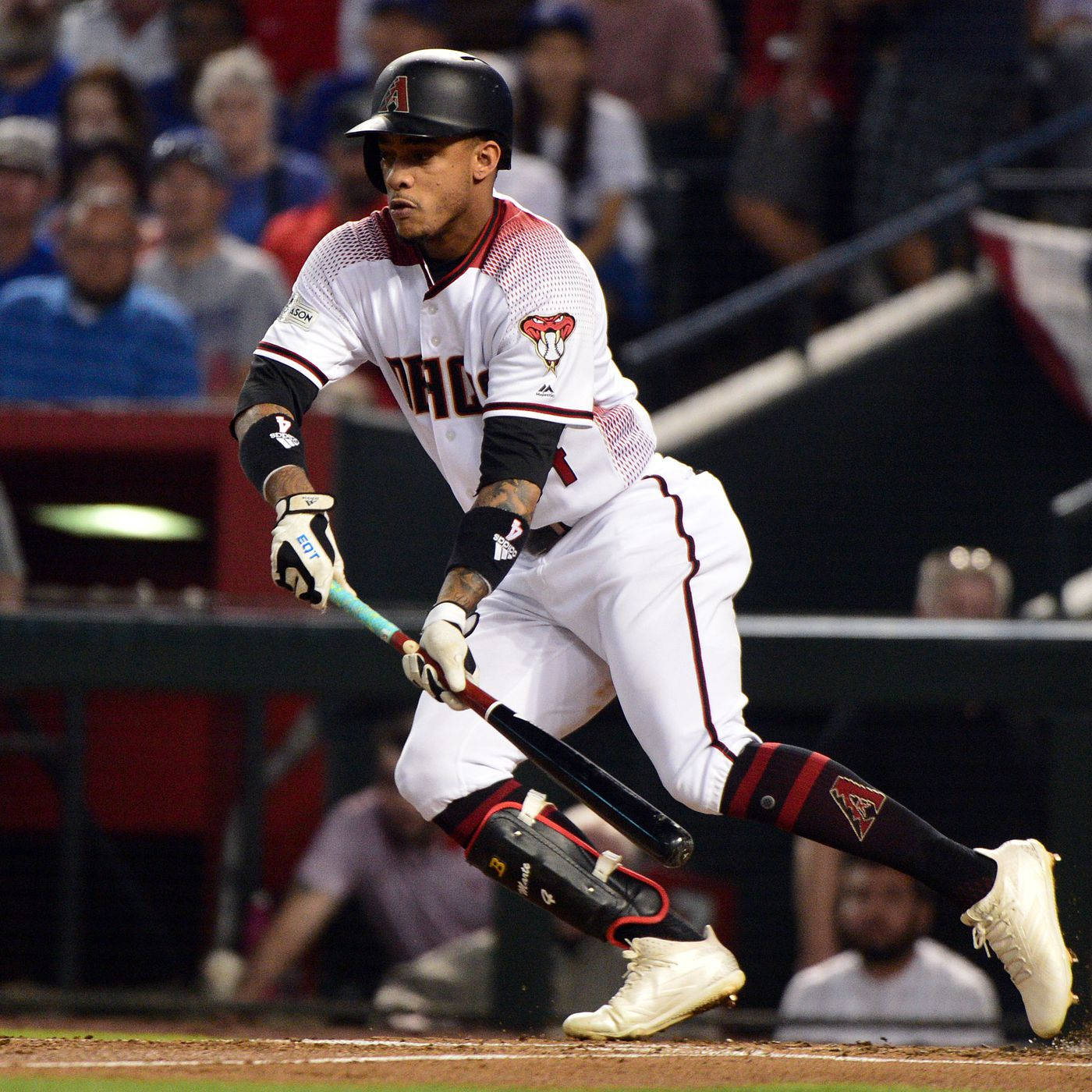 Ketel Marte 握緊棒球棒 壁紙 — 一名身穿白色和紅色球衣的棒球手在球場燈光下的夜間比賽中，全神貫注地揮棒。