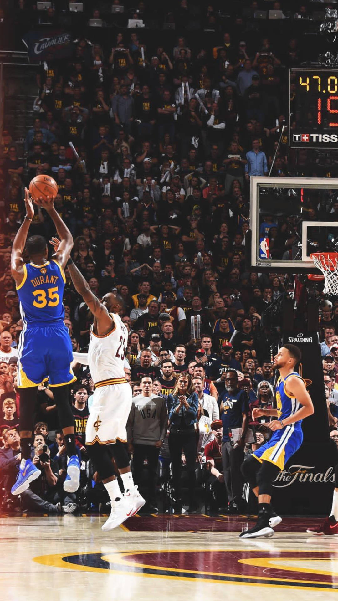 NBA總決賽期間，在擠滿觀眾的場館中，籃球運動員越過防守球員投籃。