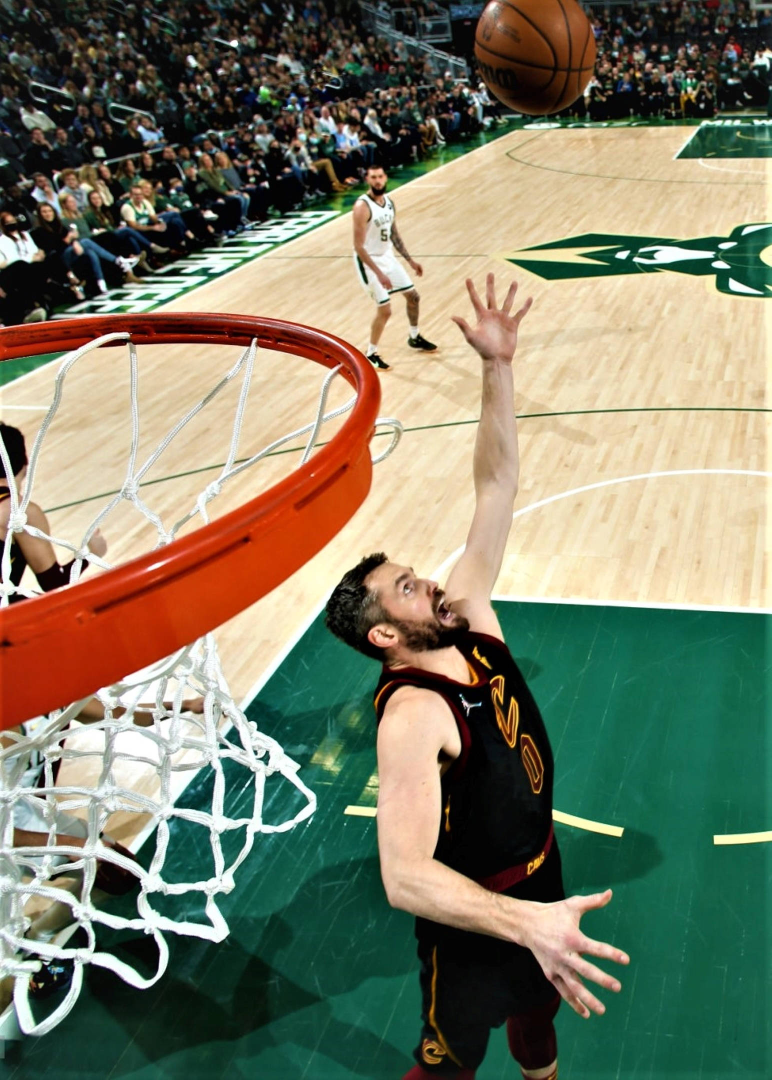 Kevin Love 籃板爭奪 壁紙 — 一名籃球運動員跳向籃框，球在空中，防守球員在球場上觀看。