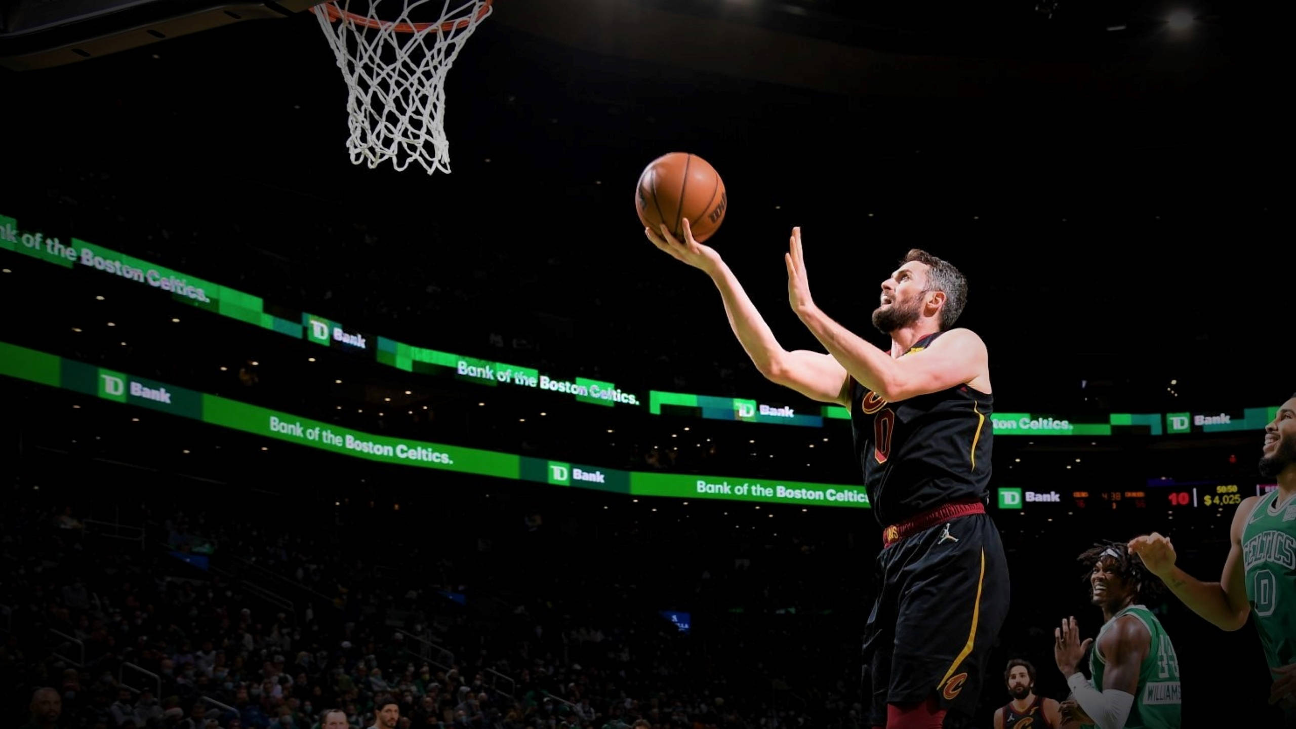 Kevin Love 上籃得分 壁紙 — 一名身穿黑色球衣的籃球運動員在明亮的場館燈光下跳起投籃，觀眾在旁觀看。