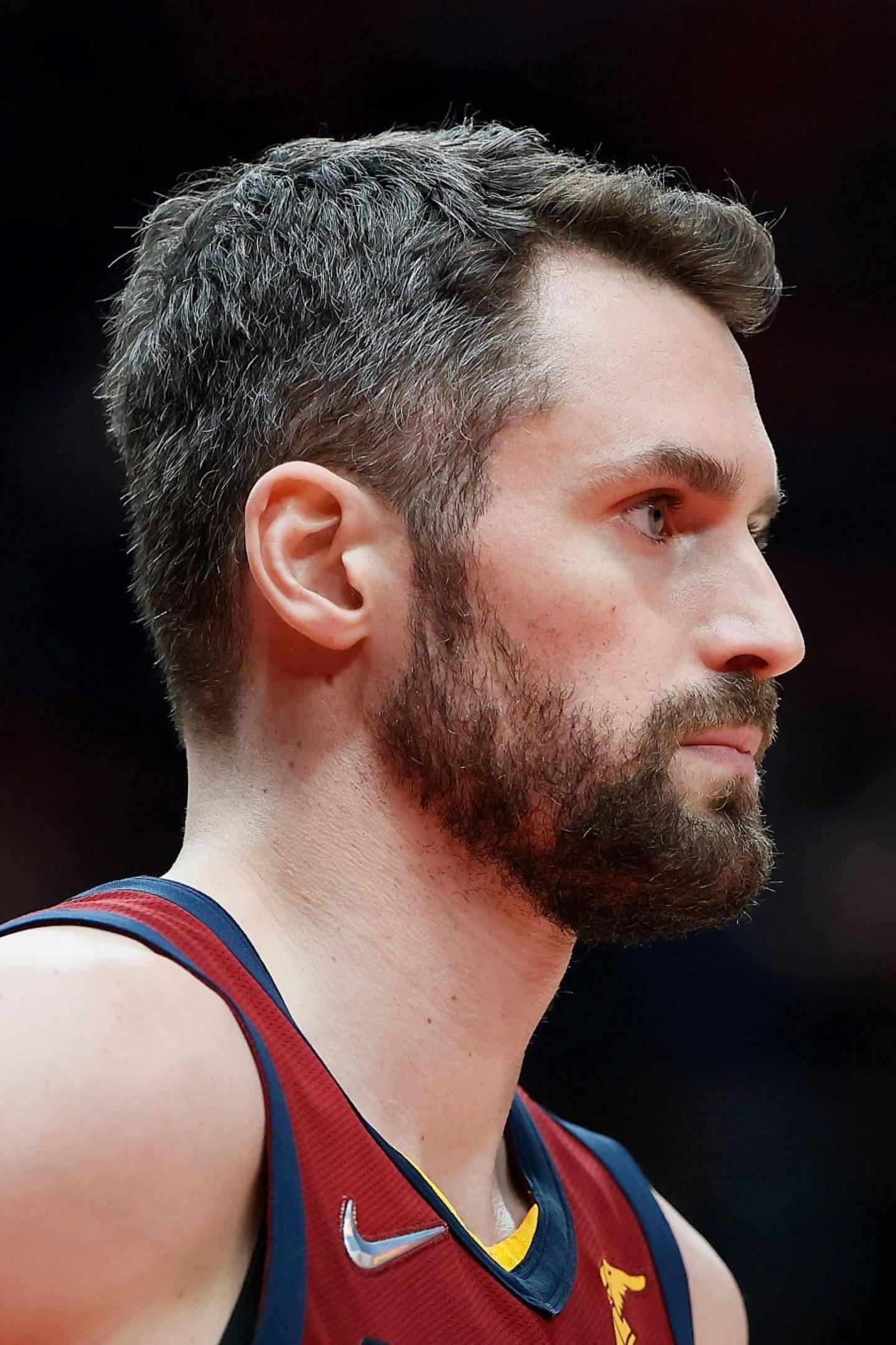 Kevin Love 側面特寫 壁紙 — 專注的鬍鬚籃球運動員穿著紅色球衣在深色背景上的特寫側面。