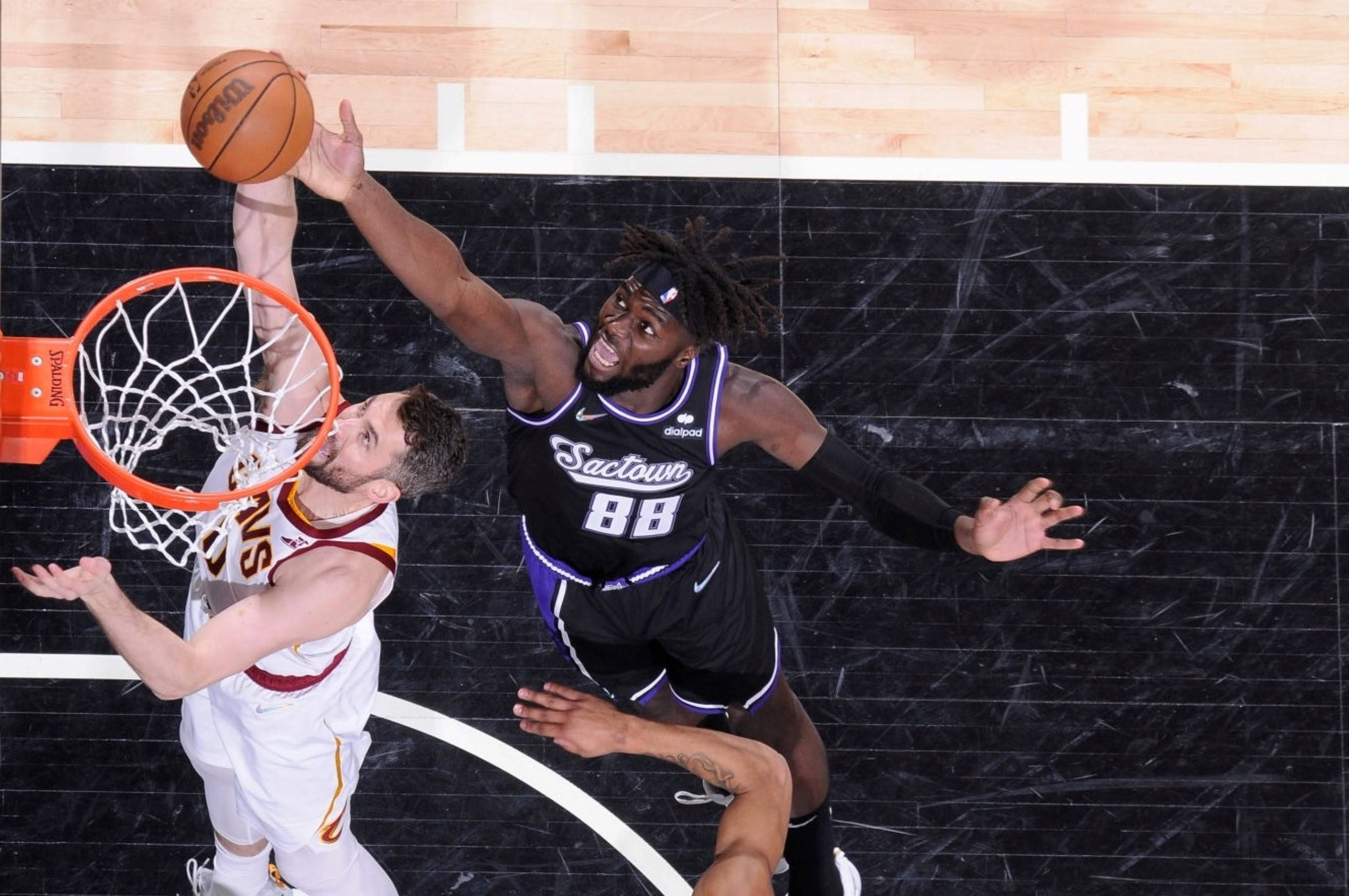Kevin Love 對戰 Queta 掩護 壁紙 — 一名身穿黑色 'Sactown 88' 球衣的籃球運動員跳起封阻投籃，而一名身穿白色球衣的對手則嘗試在籃框附近得分。