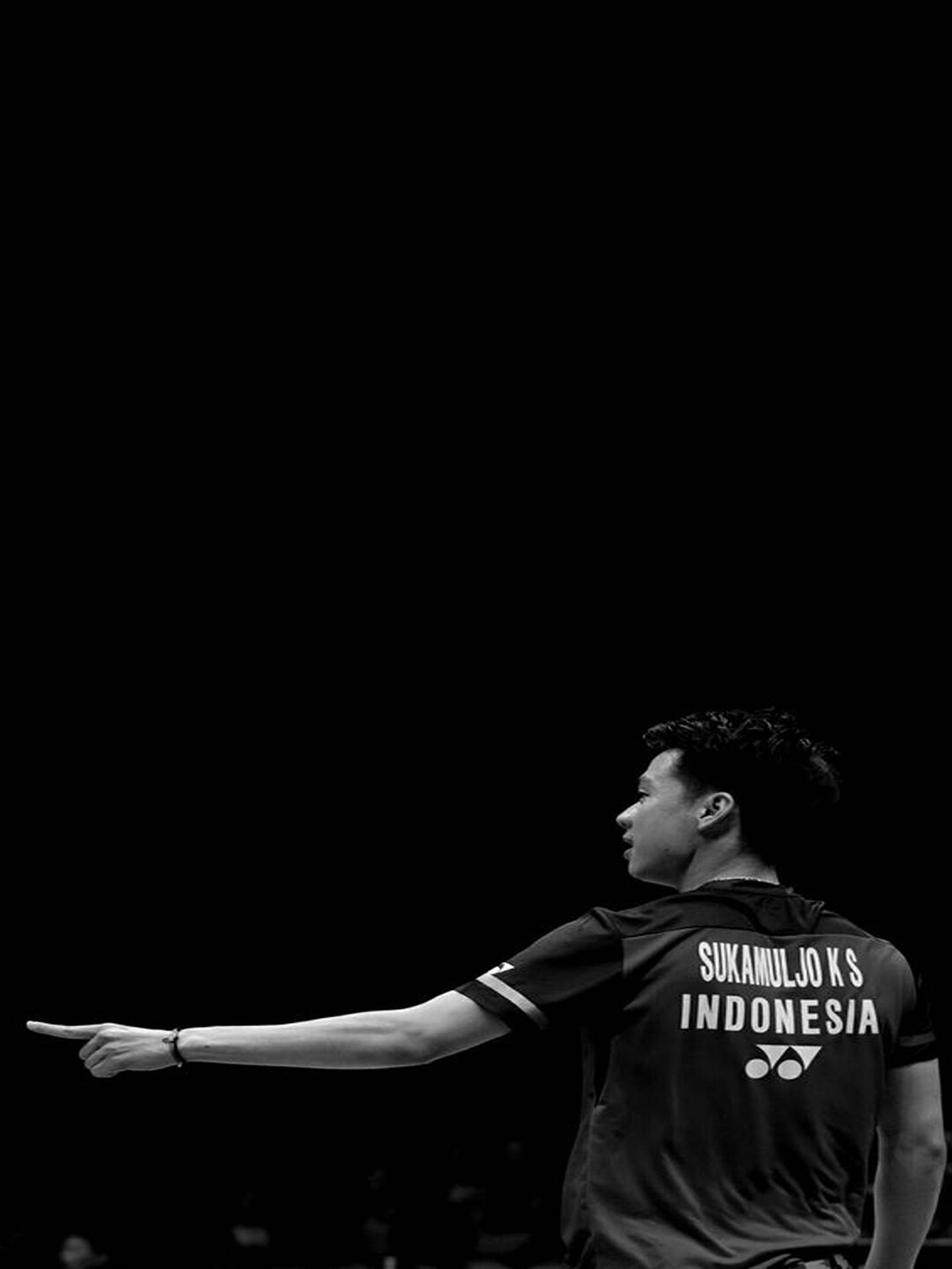 Kevin Sanjaya 領先羽毛球賽事 壁紙 — 印尼羽毛球運動員Sukamuljo KS在黑暗背景下強烈向前指的黑白肖像。