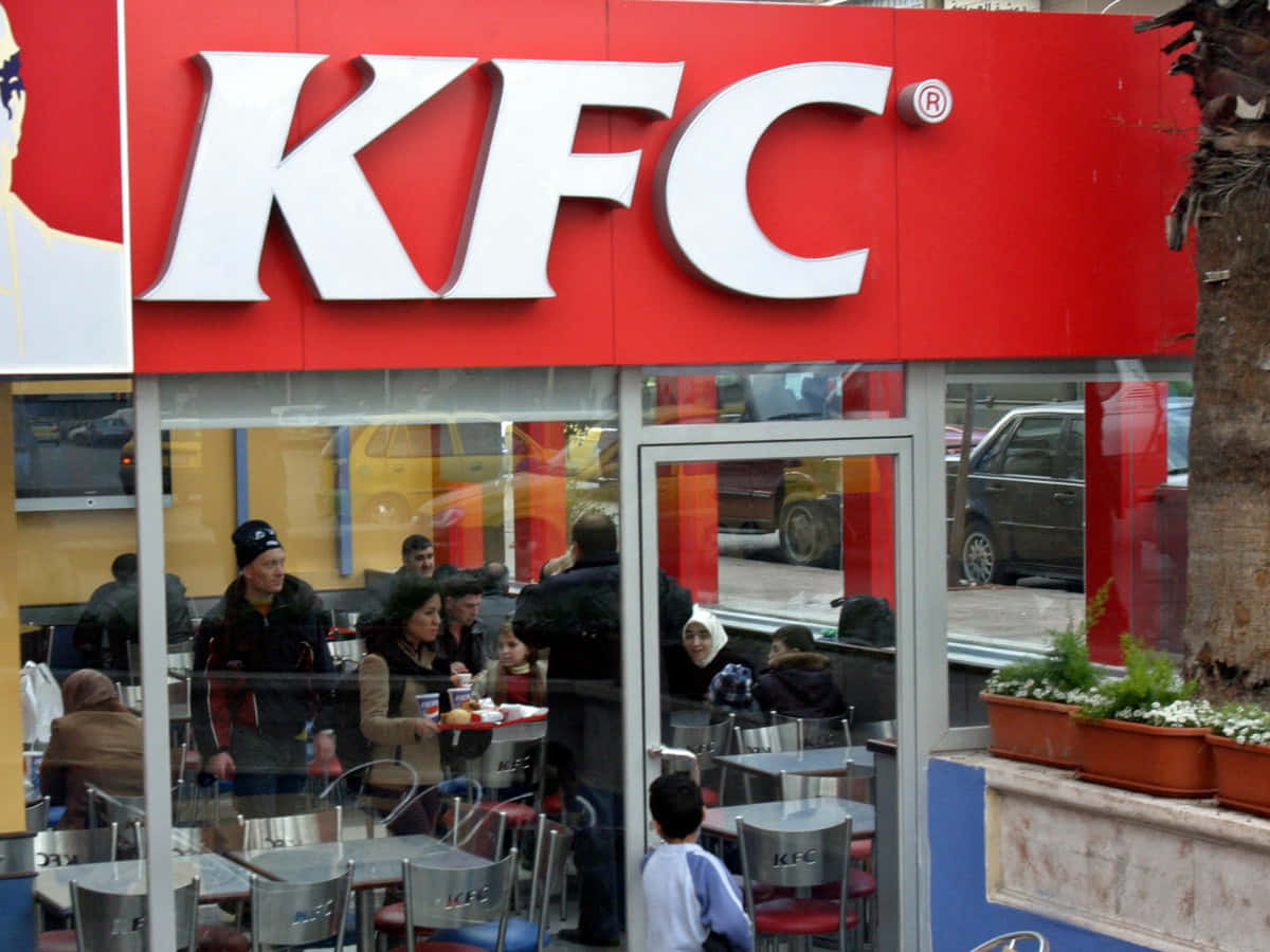 人們在帶有紅色標誌和玻璃窗的KFC餐廳內用餐。