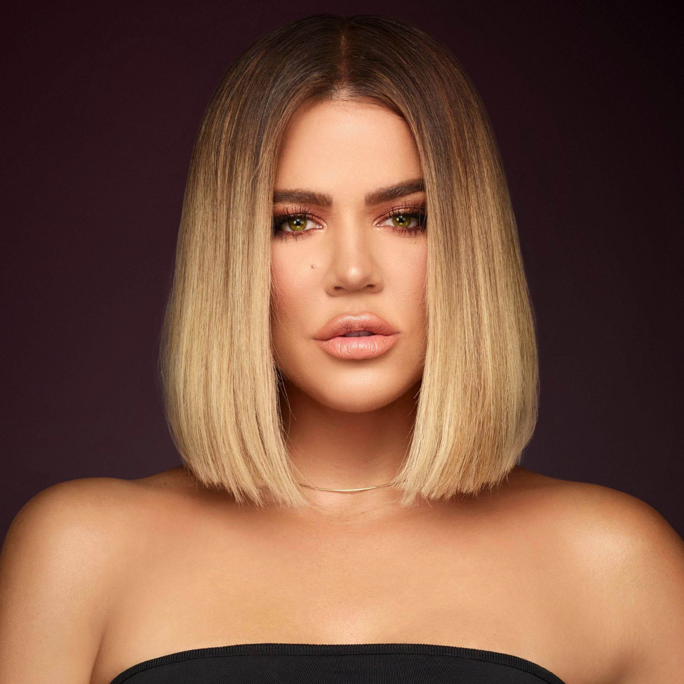 Khloe Kardashian 短髮造型 壁紙 — 一位擁有金色鮑伯頭和綠色眼睛的女性，在深紫色背景下直視鏡頭。