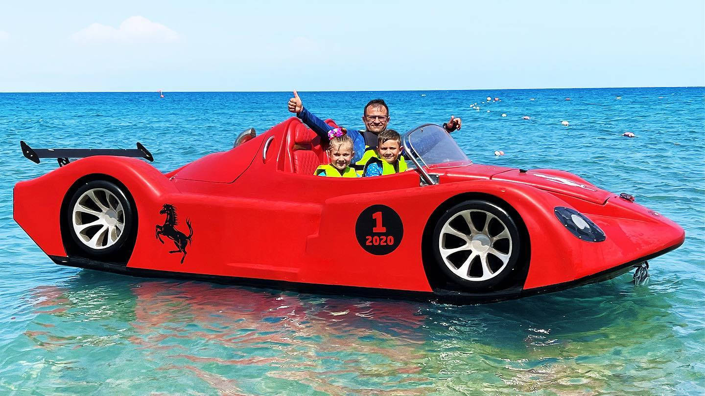 家庭乘坐紅色水陸兩用車漂浮在海水中
