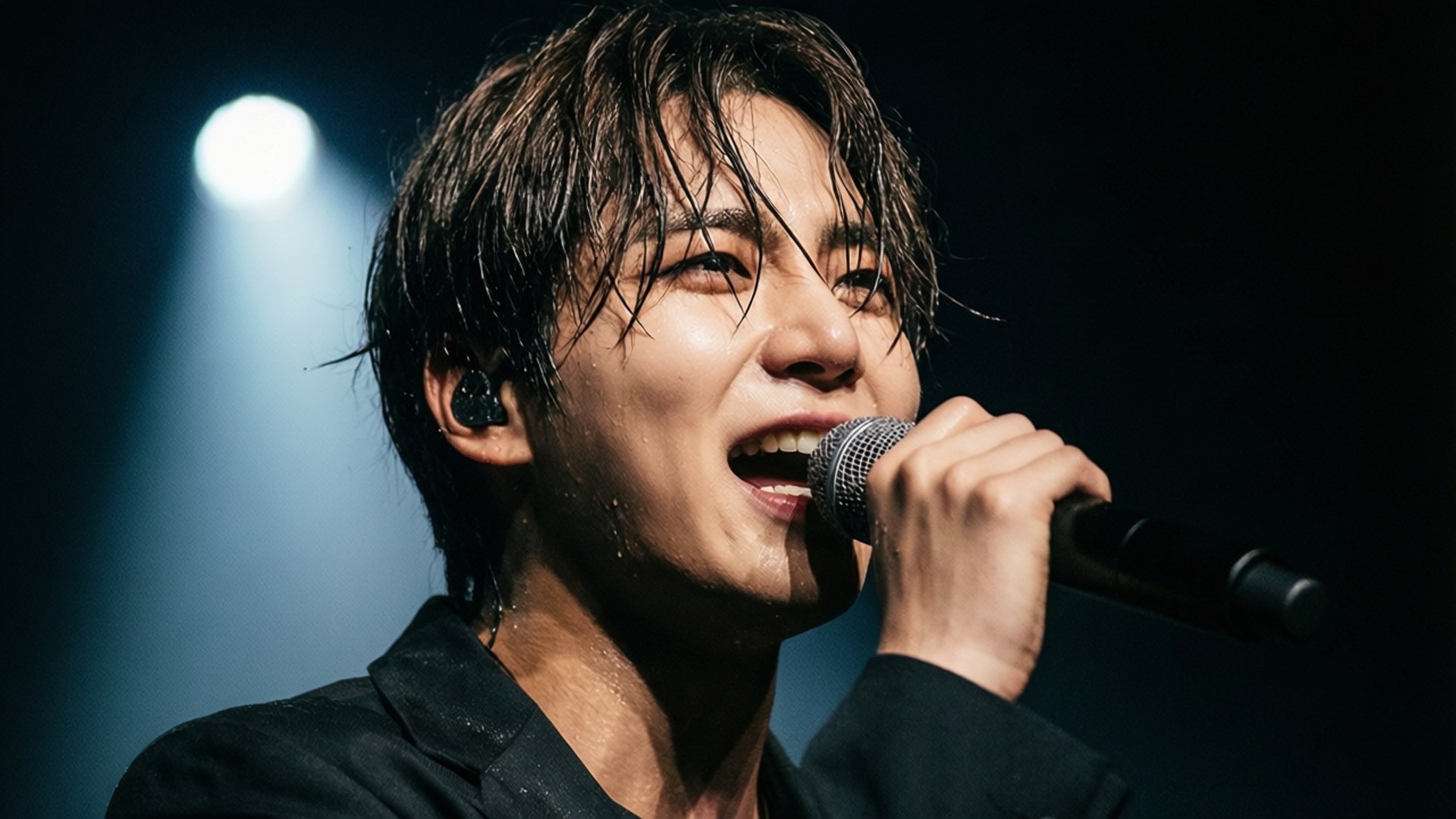男歌手在聚光燈下拿著麥克風在舞台上表演