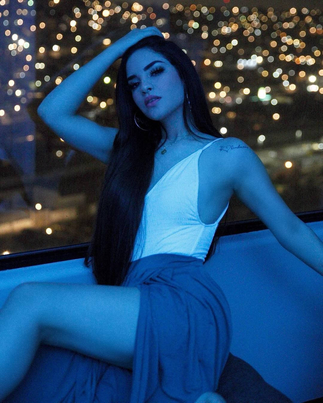 藍光中的女性在窗邊，身後有城市燈光
