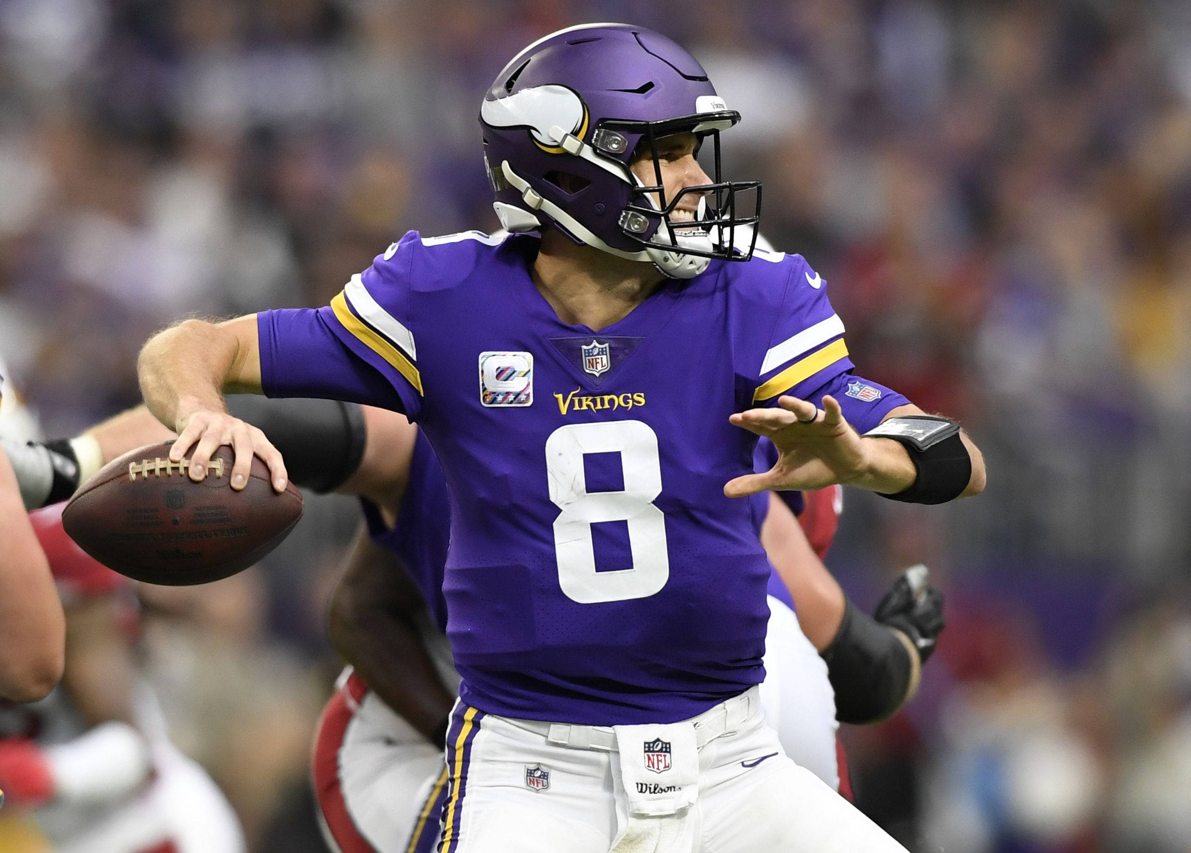 Kirk Cousins 投球瞬間 壁紙 — 明尼蘇達維京人隊的四分衛身穿紫色8號球衣，在體育場燈光下準備在比賽中投擲橄欖球。