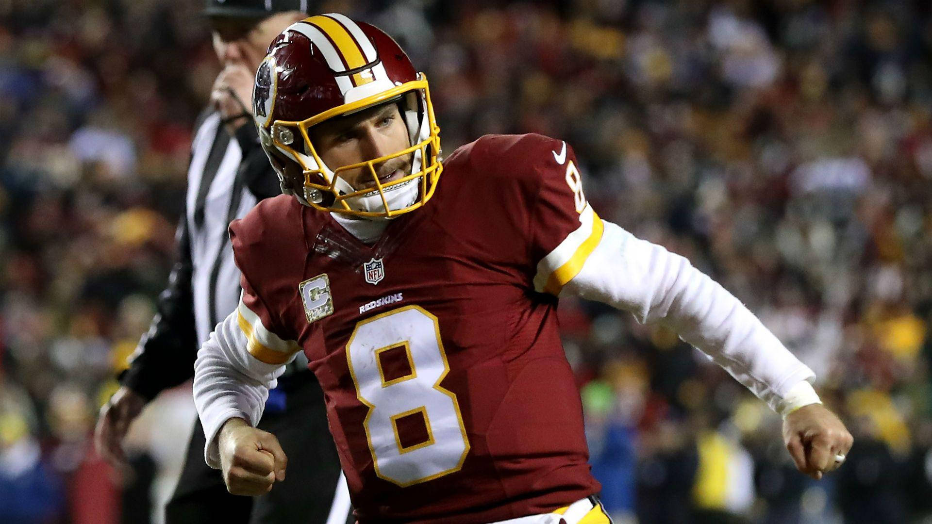 Kirk Cousins 拳頭舉起慶祝 壁紙 — 華盛頓美式足球隊的四分衛身穿栗色8號球衣，在夜間比賽的球場燈光下揮拳慶祝。